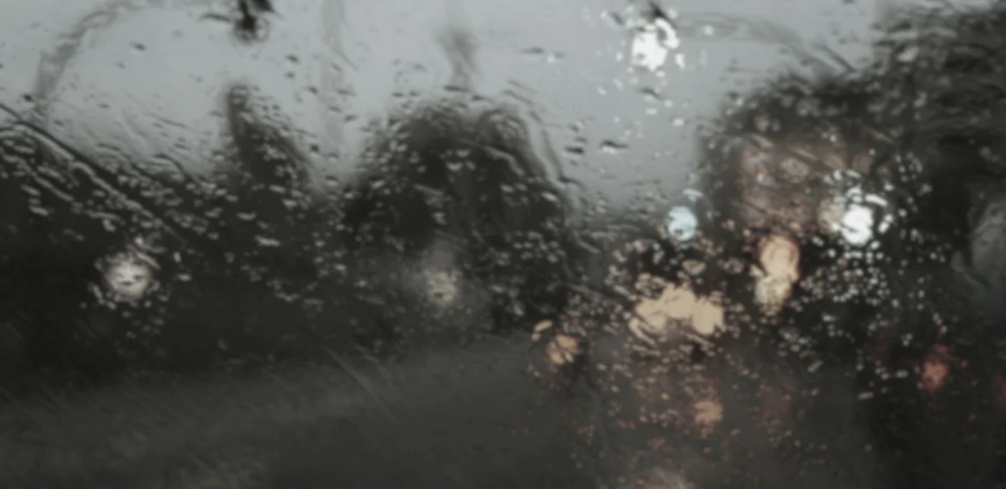 Rain-covered windshield with blurred city lights in the background