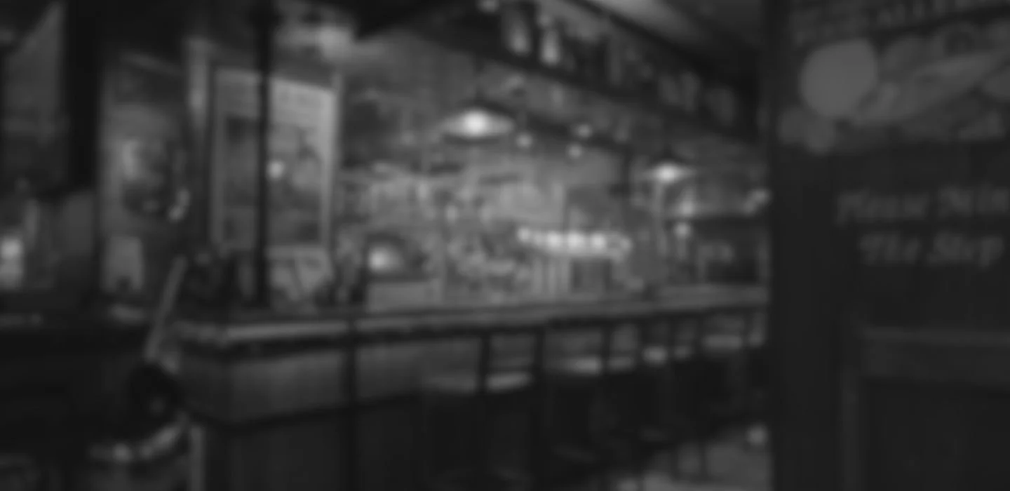 Blurred black and white image of a storefront or display case, with shelves and various items inside.