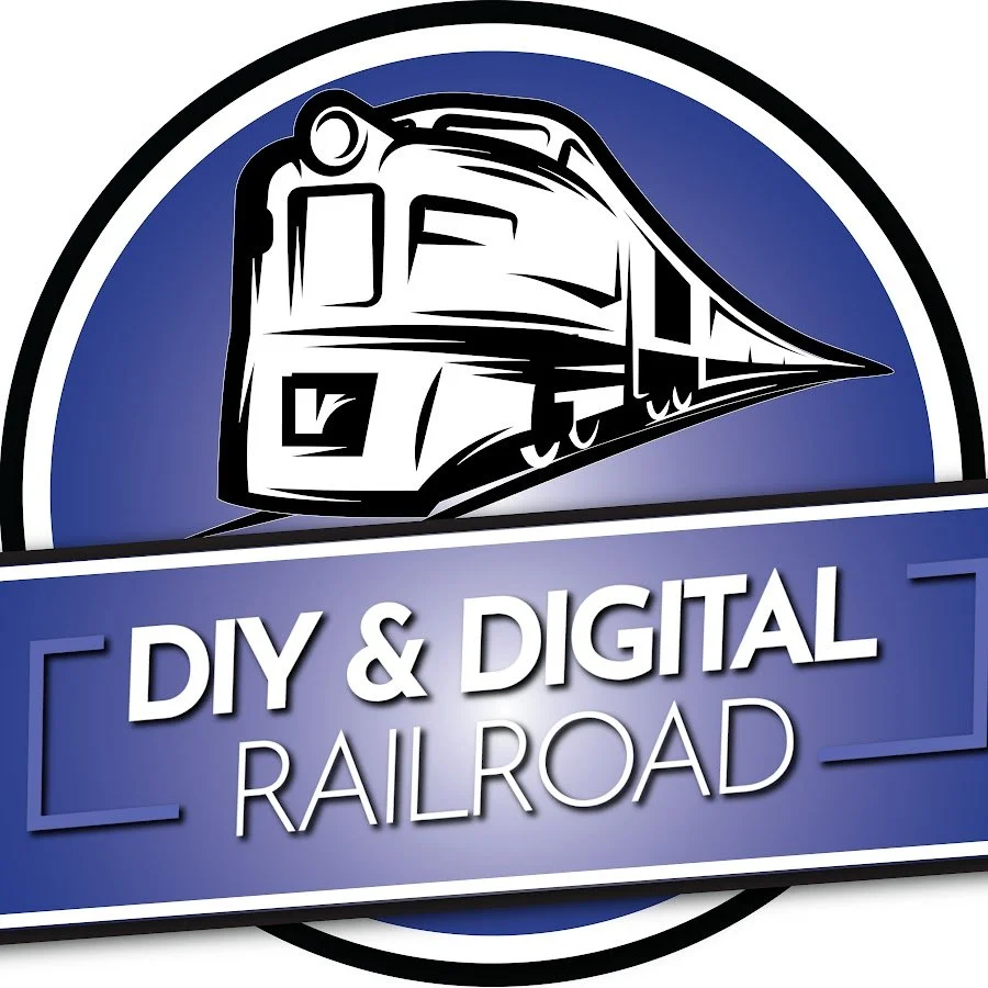 A logo for DIY & Digital Railroad featuring a stylized train engine in black and white on a blue circular background with a blue banner beneath that includes the text 'DIY & DIGITAL RAILROAD' in white.