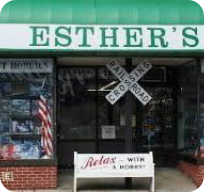 Storefront with green sign reading 'Esther's' and crossed barber poles outside.