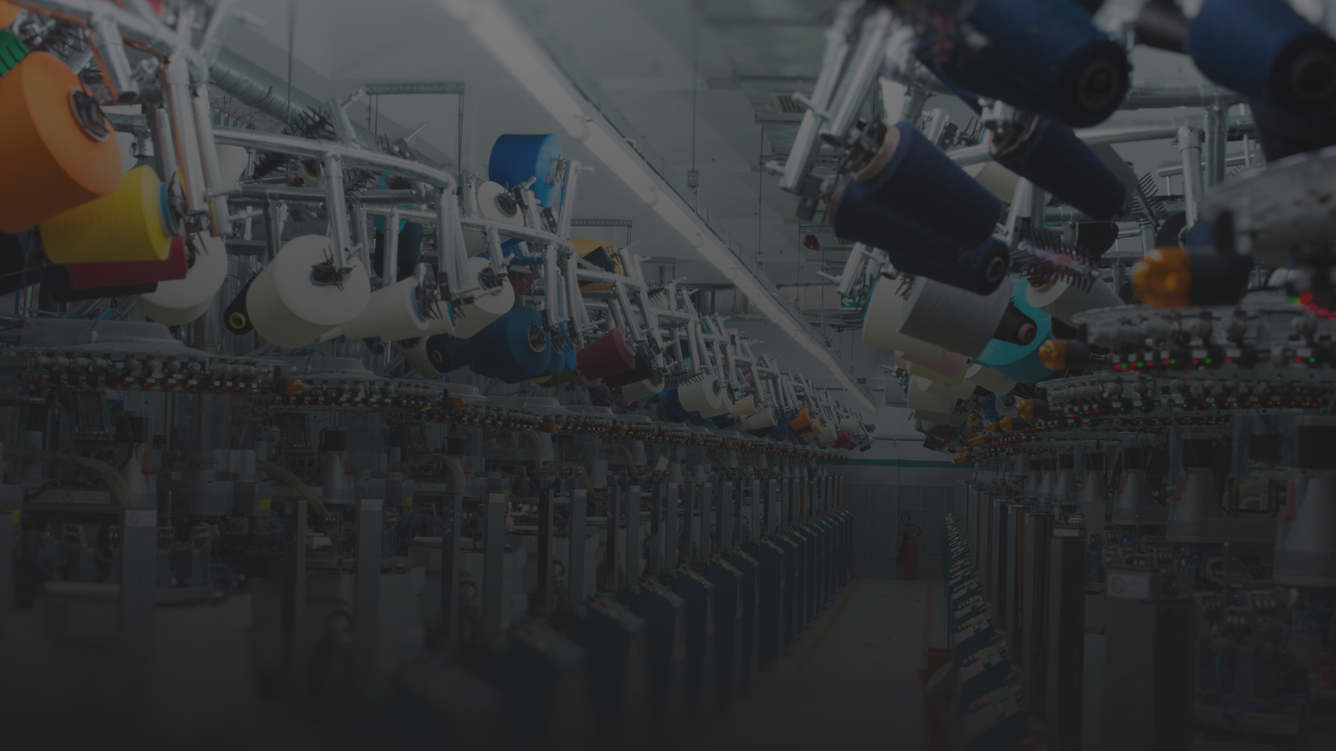 Fábrica de tecidos com máquinas de costura industriais e bobinas de linha coloridas.