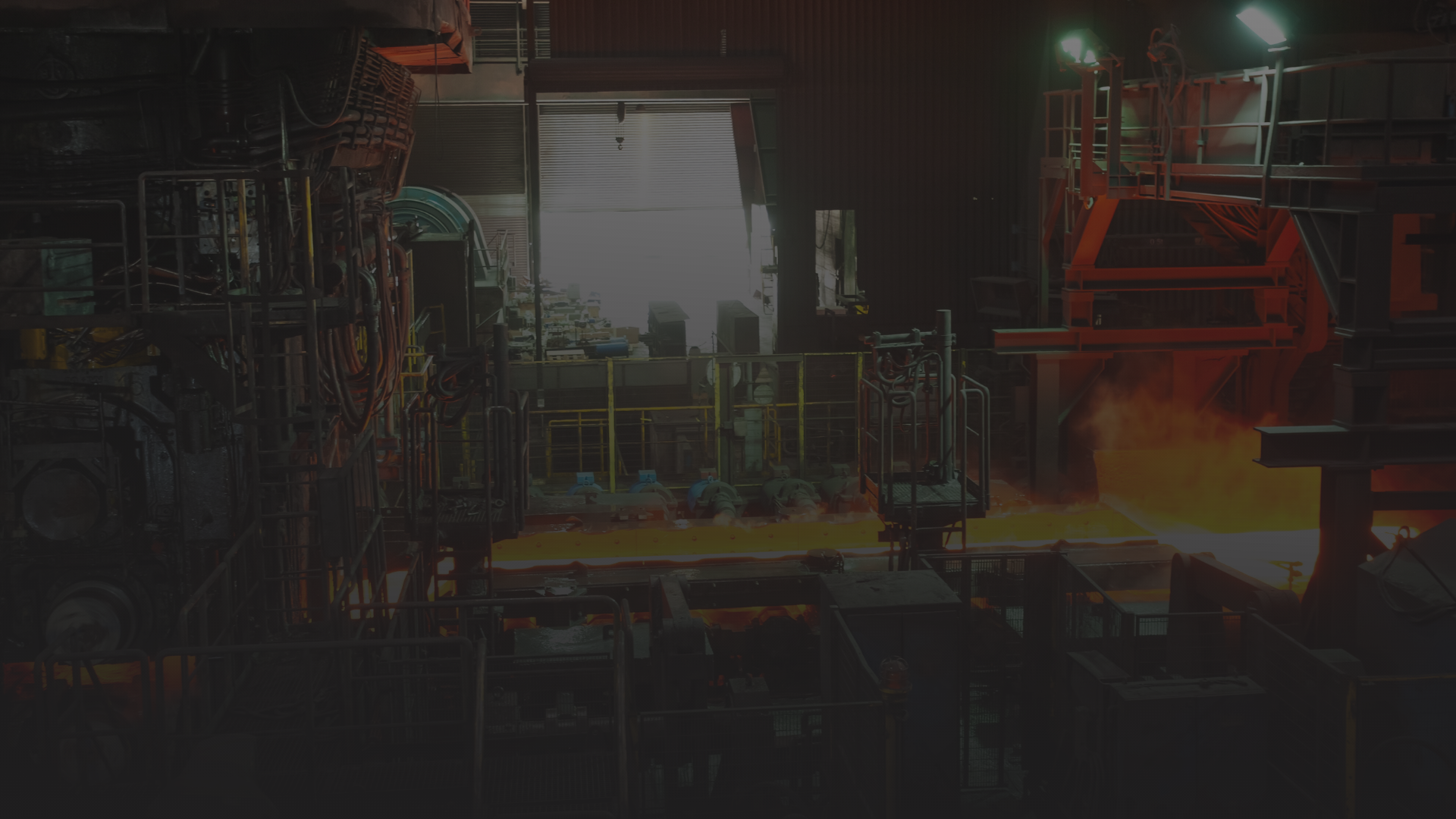Interior de uma fábrica de processamento de metal com alta temperatura, equipamentos industriais e fluxo de metal fundido quente.