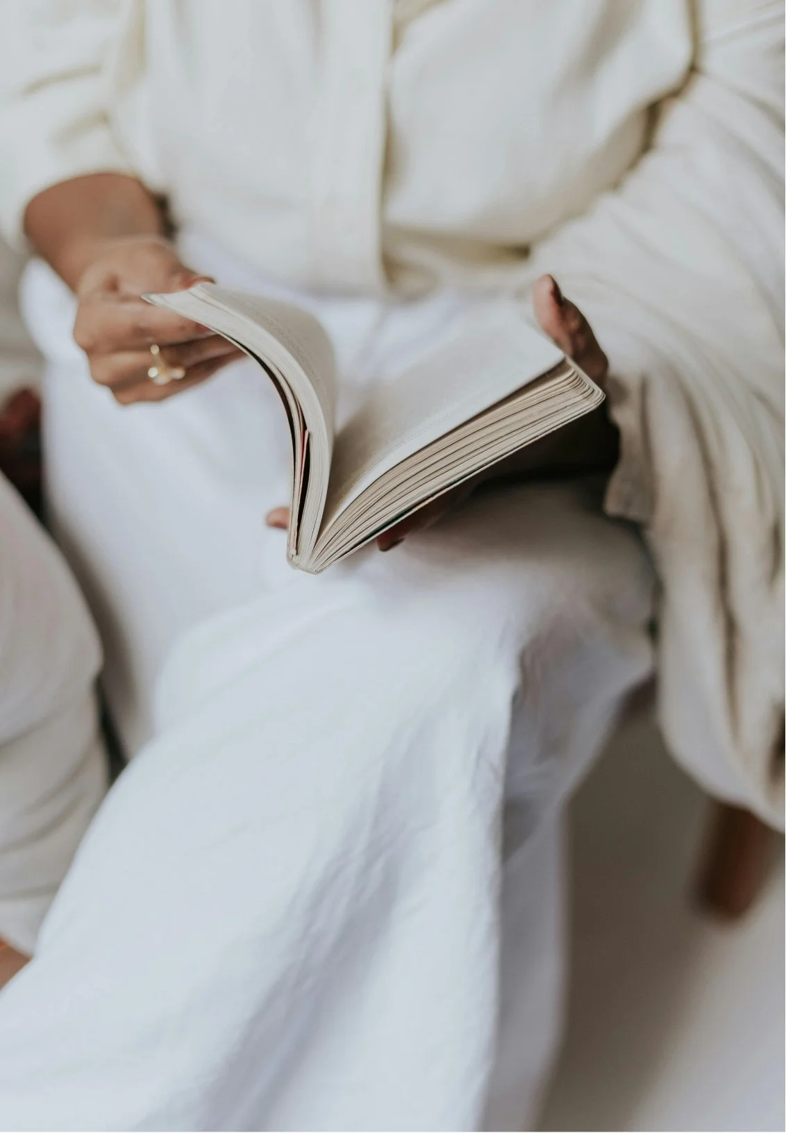 Person in white clothing reading an open book.