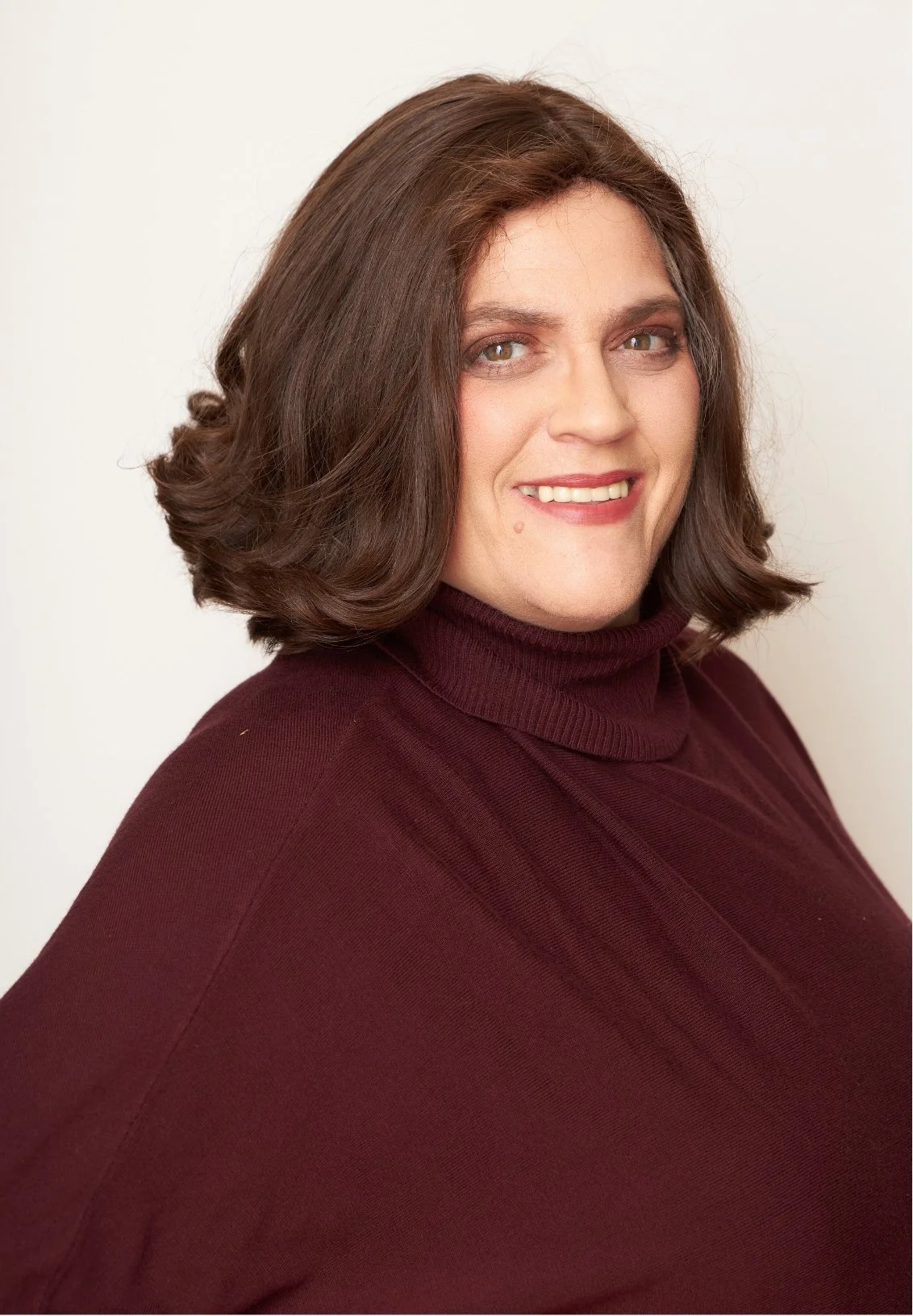 Rivkah Cunin, couples therapist in Los Angeles, smiling, wearing a burgundy turtleneck sweater against a plain light background.