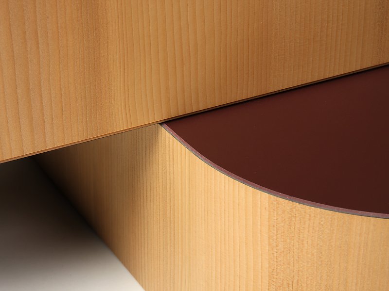 Nahaufnahme eines modernen Holzmoobals, das aus zwei Teilen besteht, mit einer glatten, halbkreisförmigen Oberfläche in dunkler Farbe.