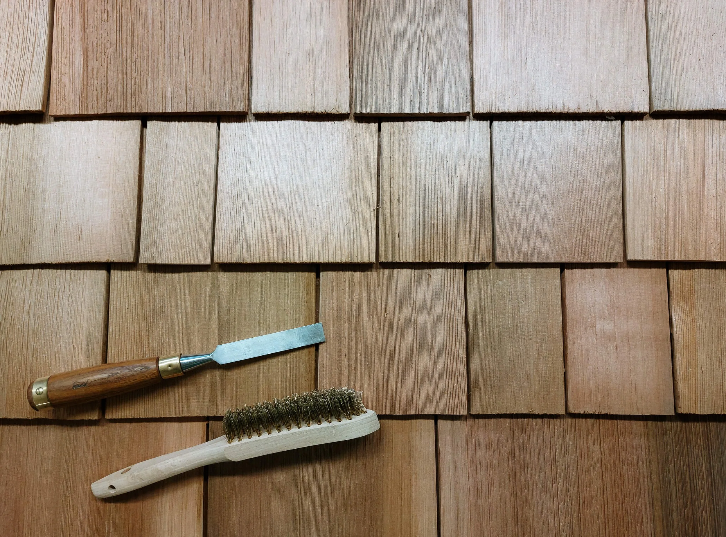 Verschiedene Holzarten, eine Bürste und eine Holzstickerei auf einem Holzfurnier
