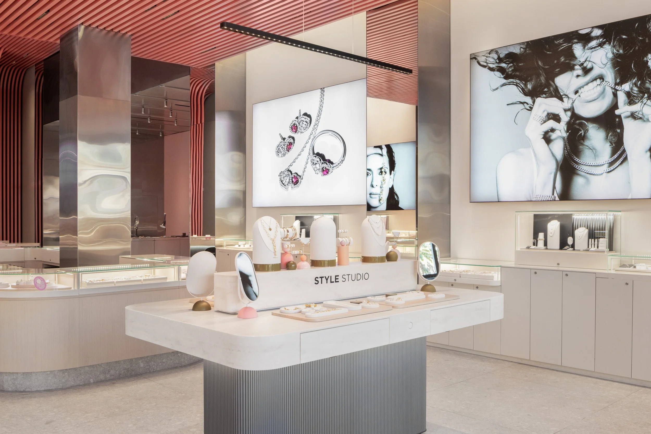 Jewelry display in a modern retail store with black-and-white large photographs of a woman wearing jewelry, and jewelry pieces like necklaces, rings, and earrings showcased on white busts and trays.