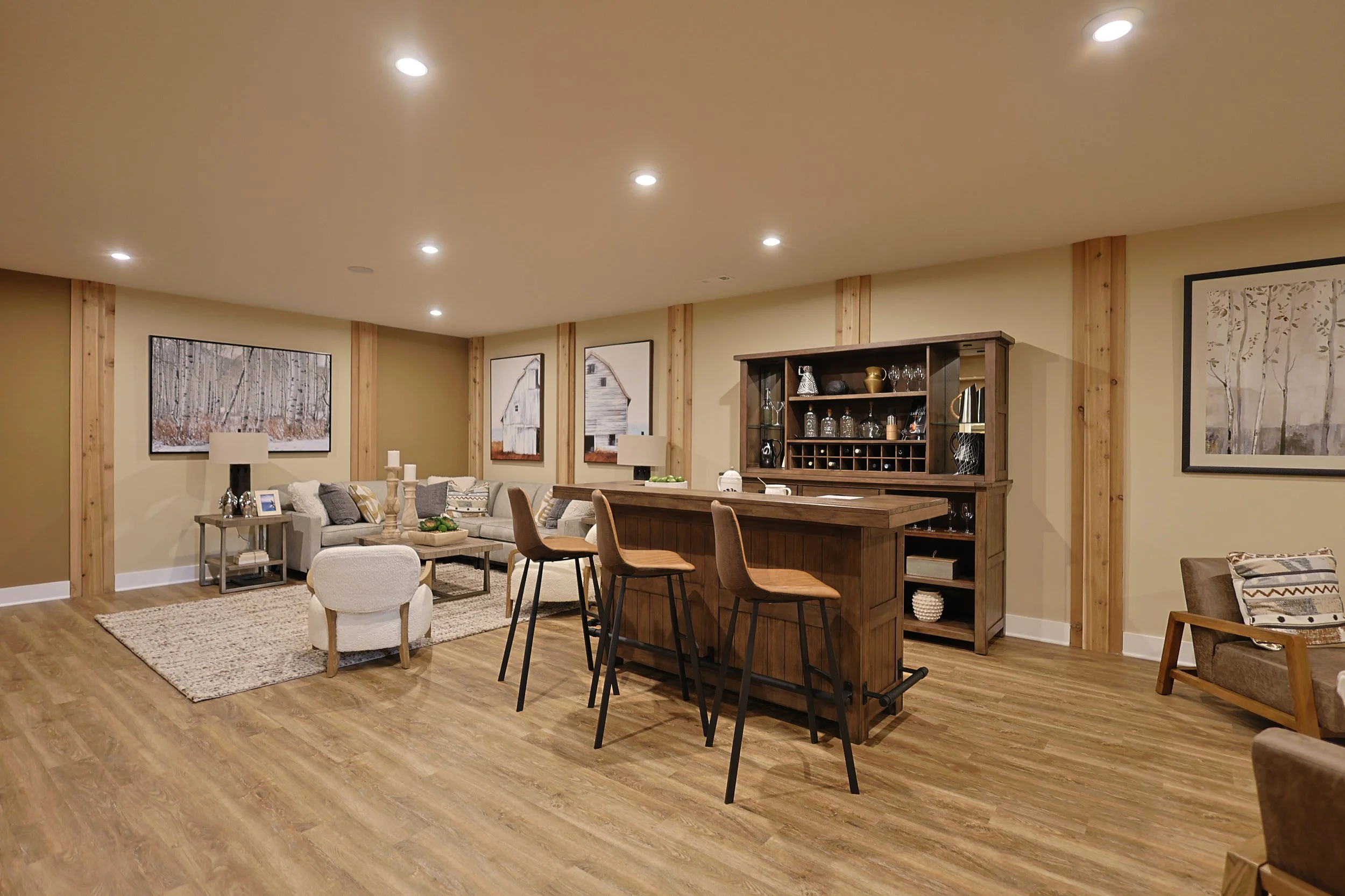 Living room with beige walls, wood trim, hardwood floors, seating area, and a bar with barstools.