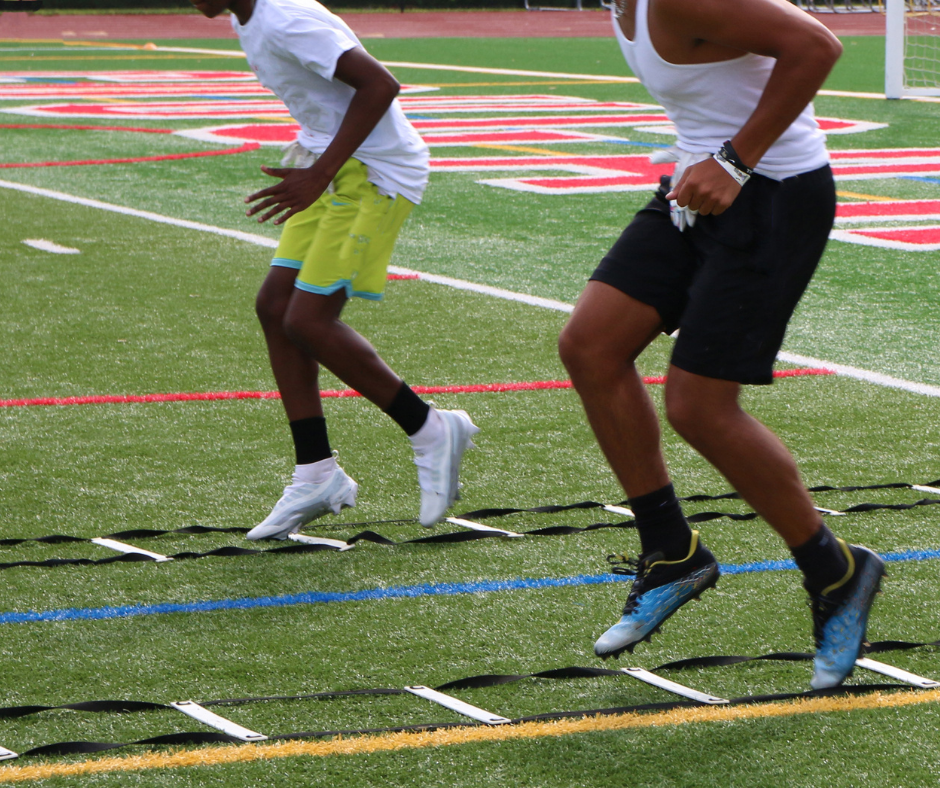 Two people running on a turf field with agility ladder drills.
