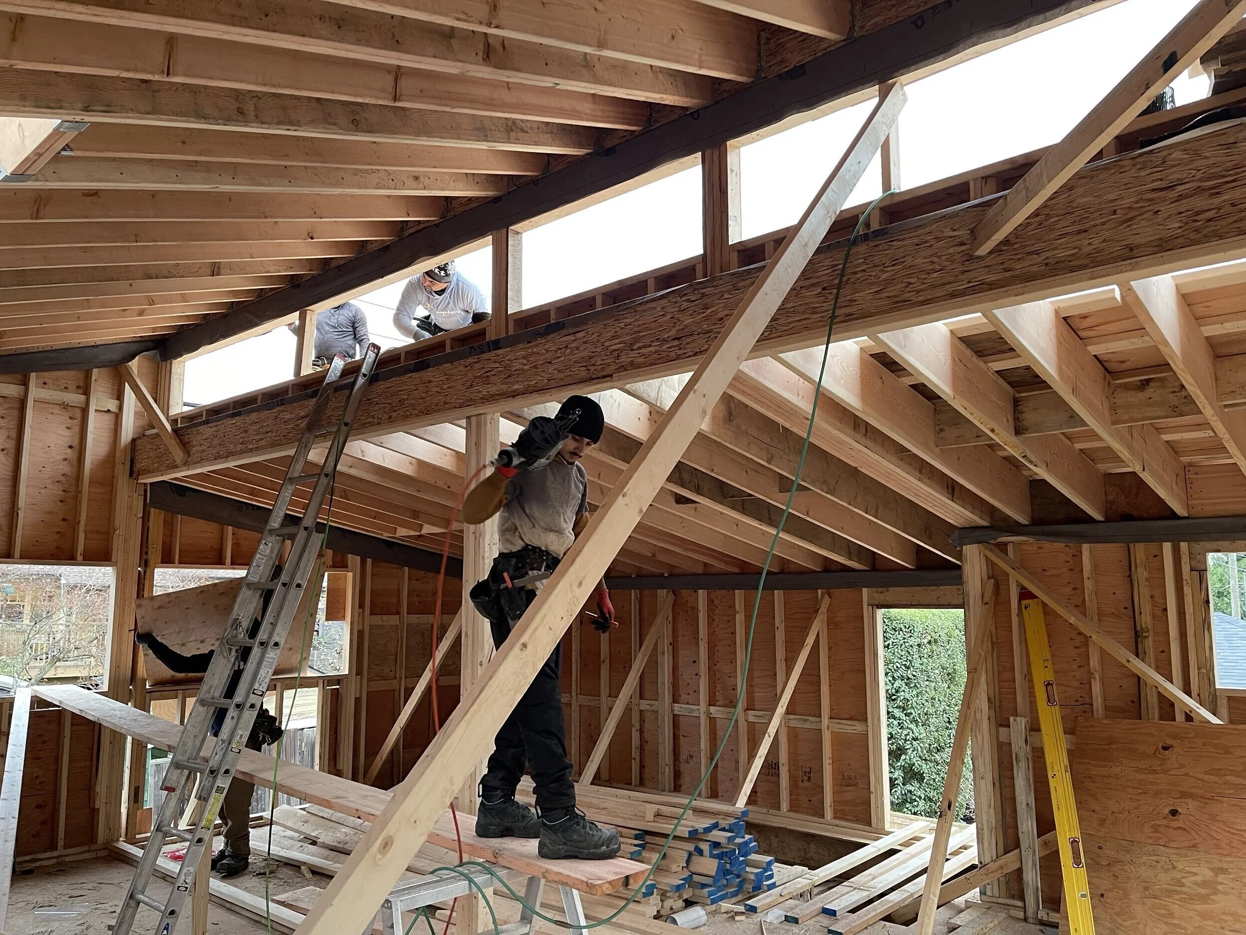 Construction workers building the interior of a house, with wooden framing and scaffolding.