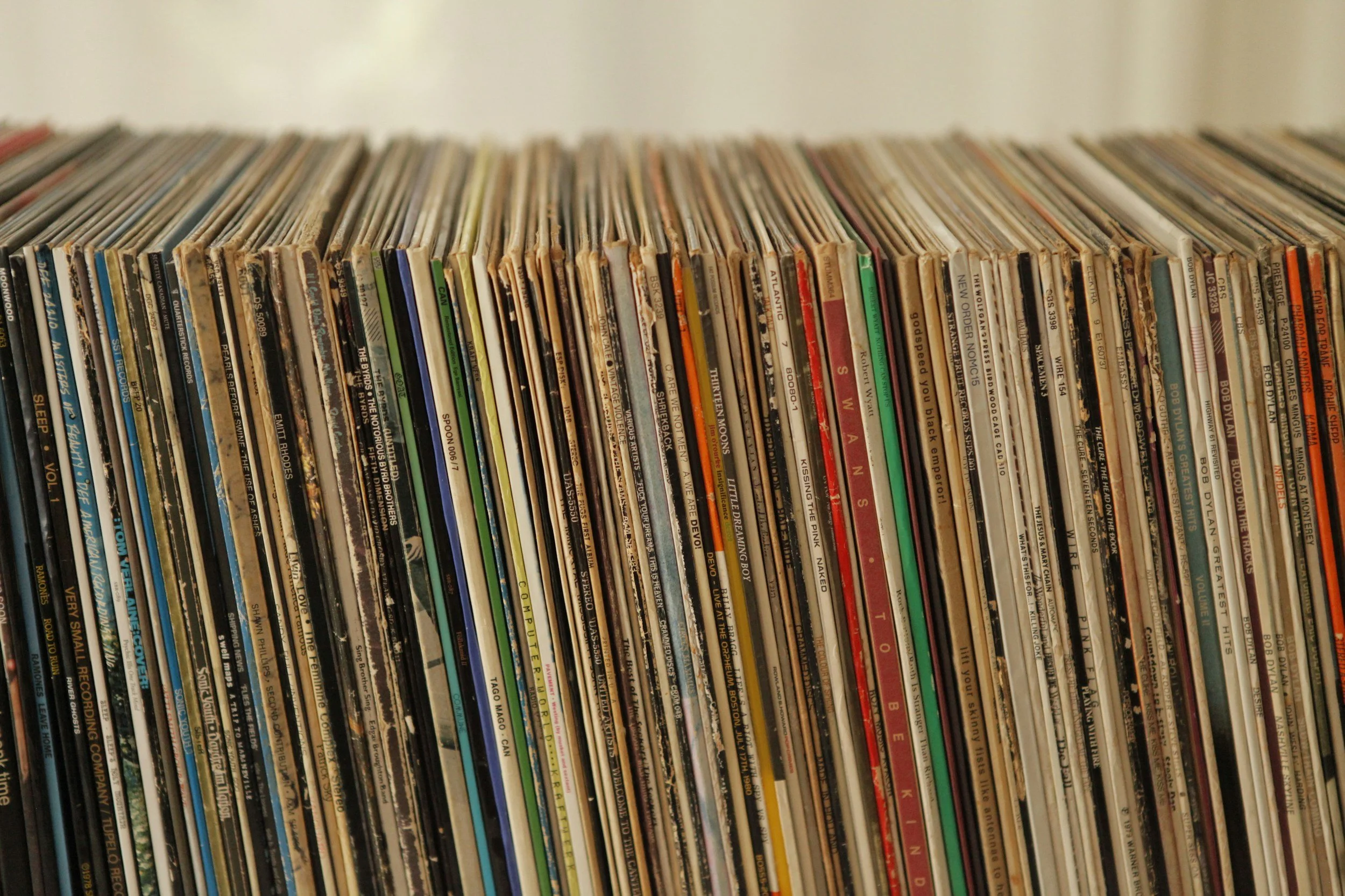 Close-up of a collection of vinyl records stored vertically, showing their colorful spines with various album titles.
