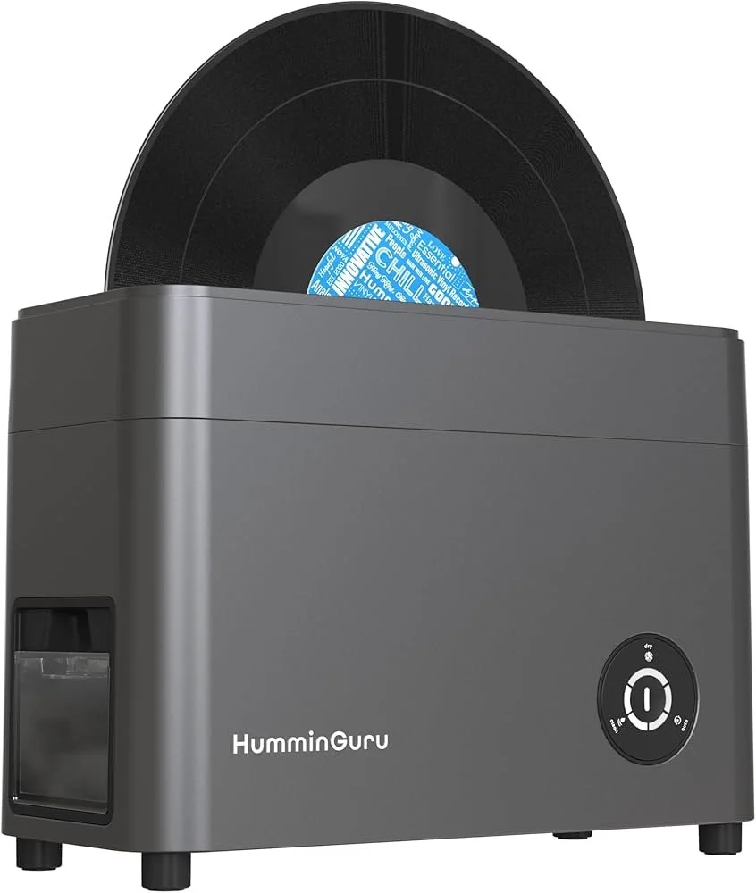 A gray vinyl record cleaner with a black spinning turntable and a display on the front labeled 'HummieGuru'.
