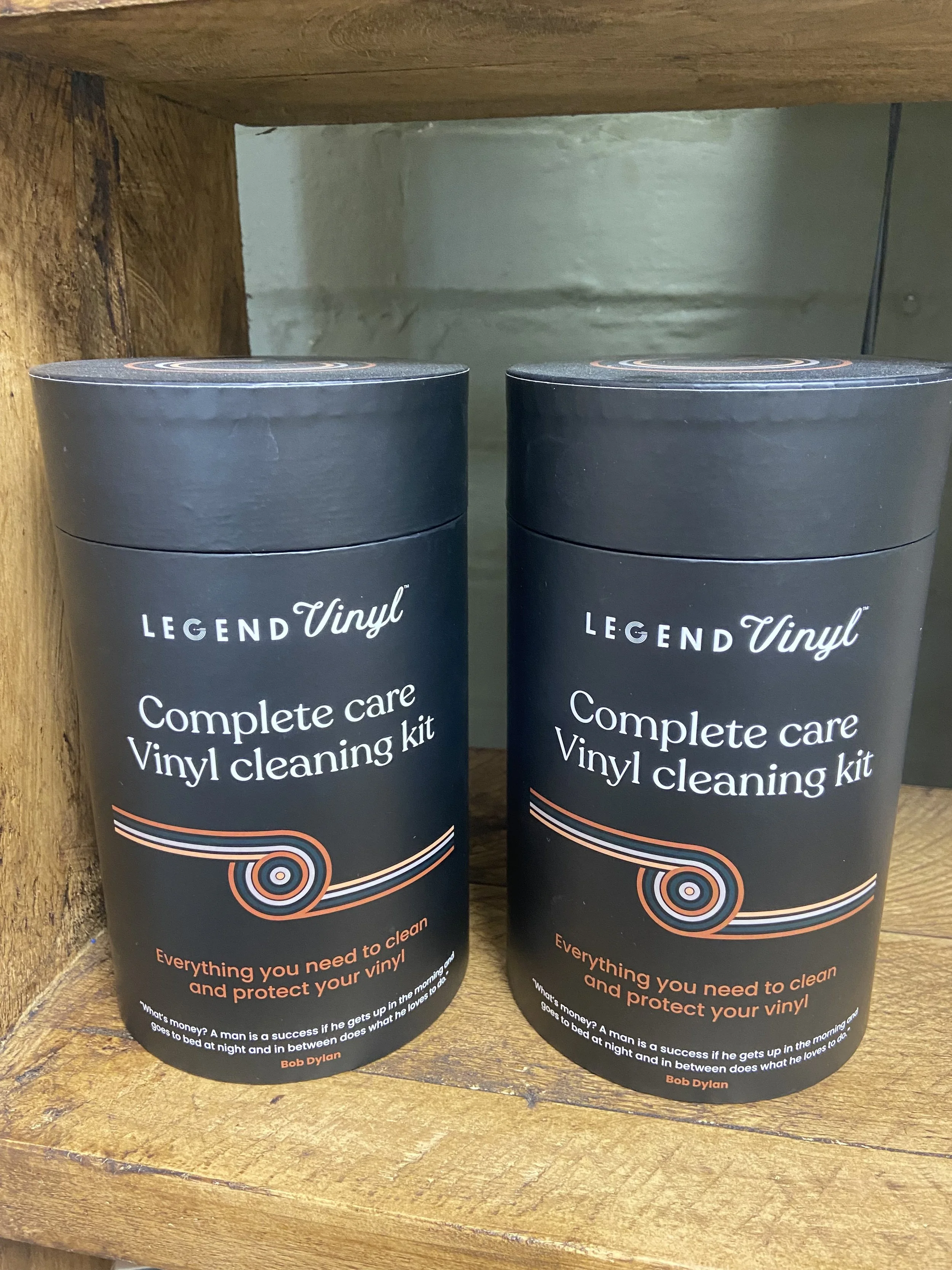 Two black bottles of Legend Vinyl Complete Care Vinyl Cleaning Kit resting on a wooden surface.