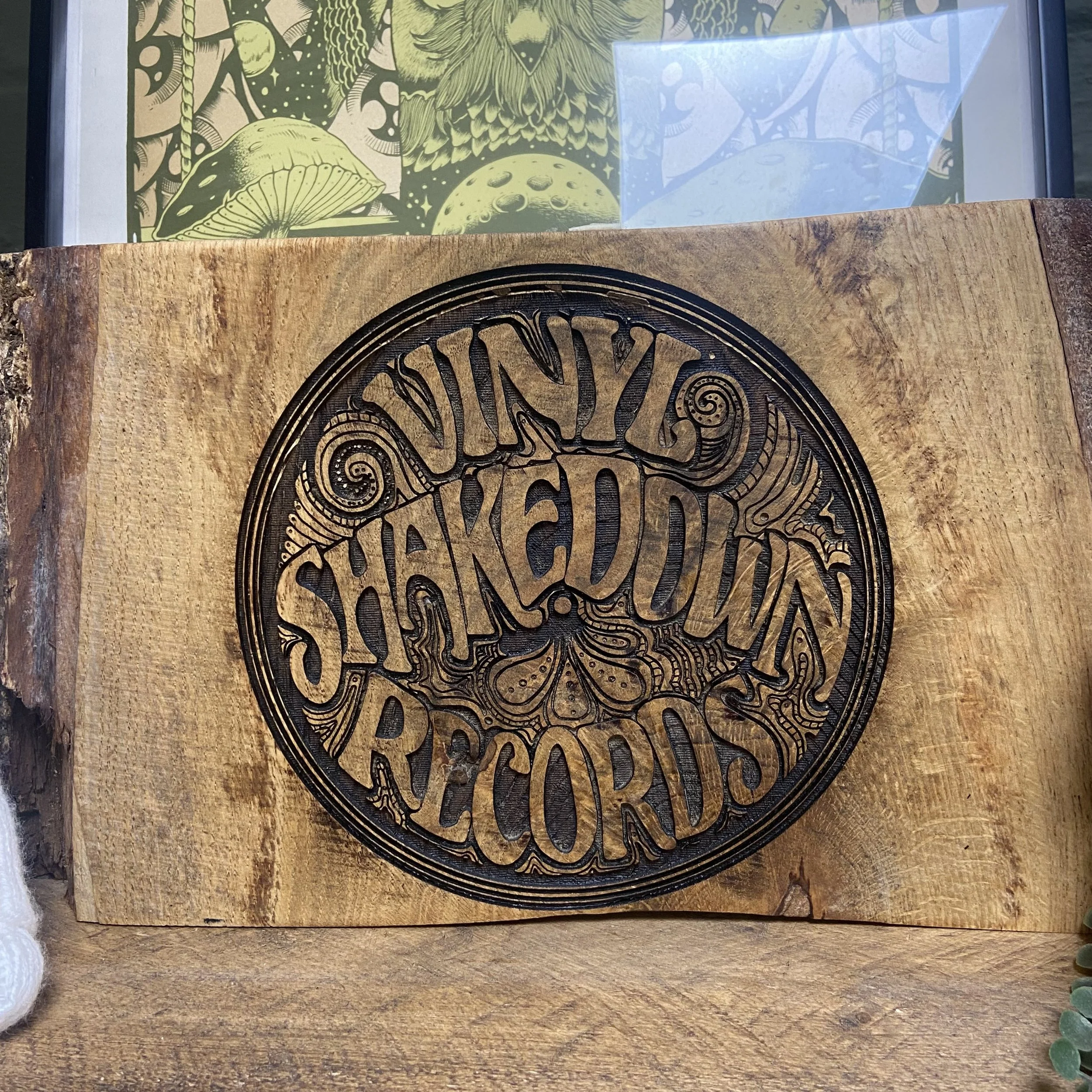 Wooden plaque with a carved tree design in the center and a background with illustrations of a mushroom, an owl, and the moon.