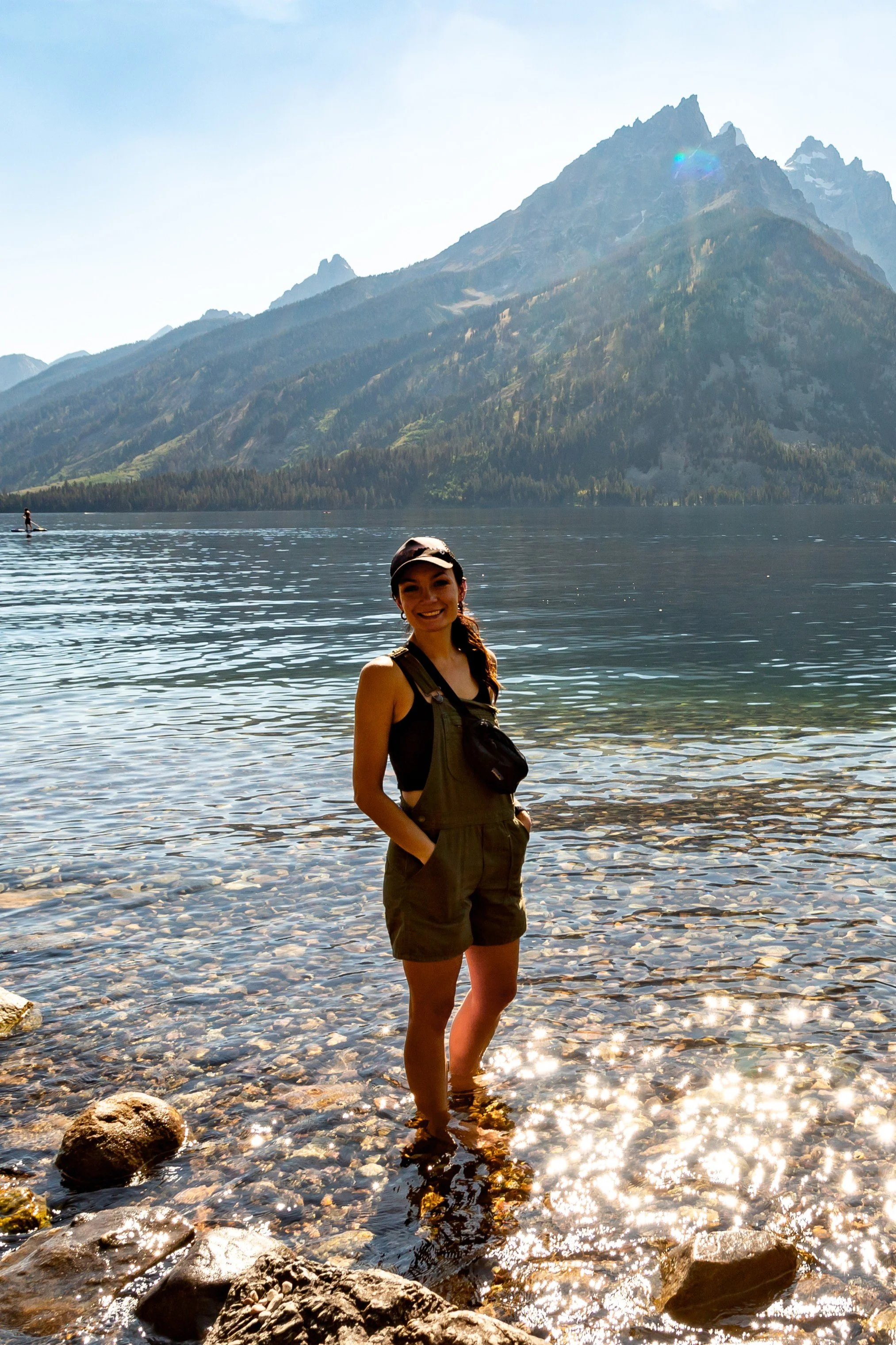 Jassi Wahlberg in outdoor gear standing in Jenny Lake with the Grand Tetons in the background.