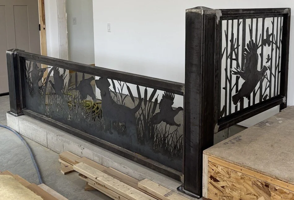 A metal railing with a wildlife design featuring silhouettes of animals such as deer, bears, and birds, set in a natural outdoor scene.
