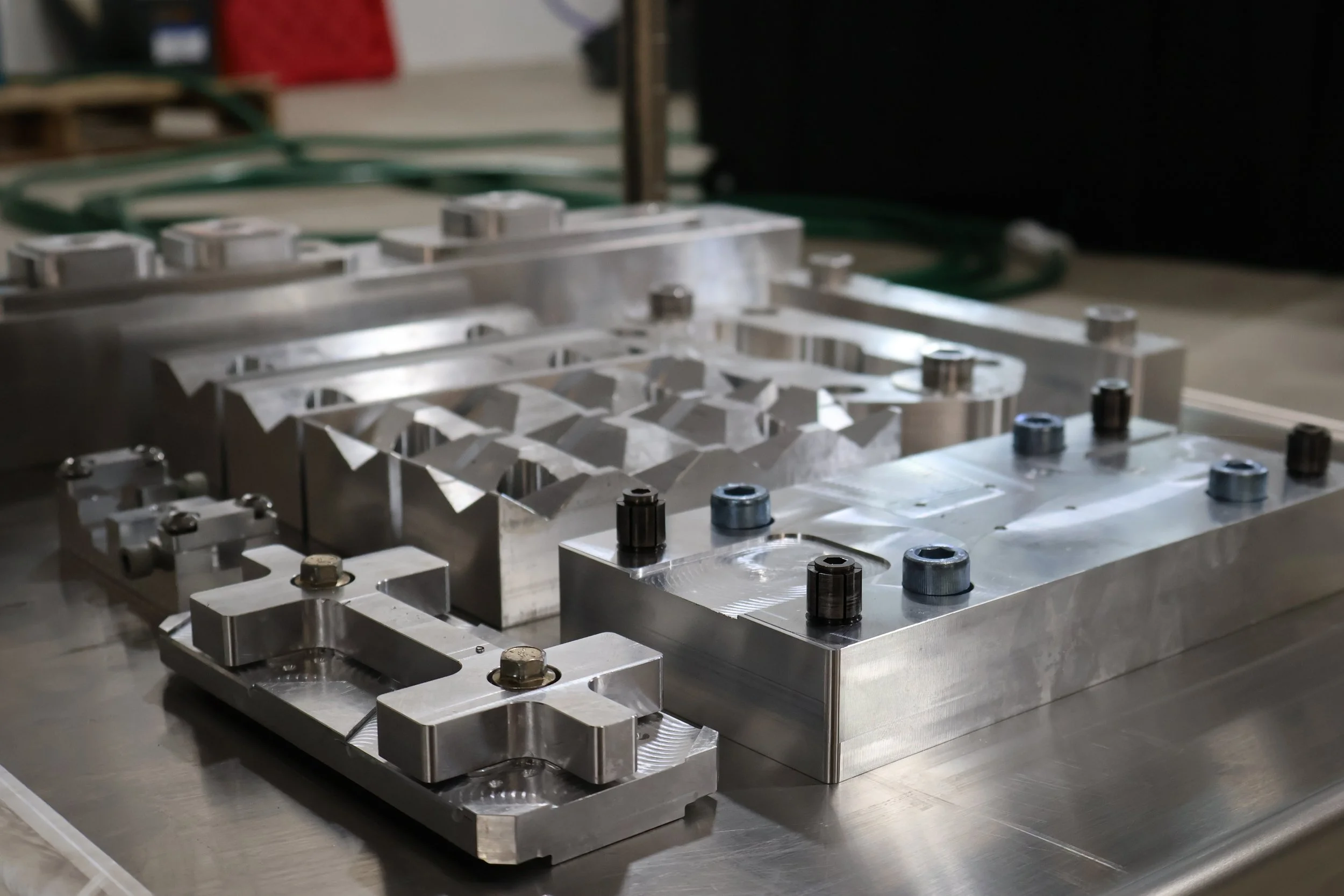 Close-up of a metallic mold or industrial manufacturing tool on a workbench in a factory setting.