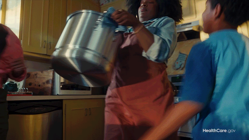 Person pouring a beverage from a large metal pot while children watch in a kitchen.