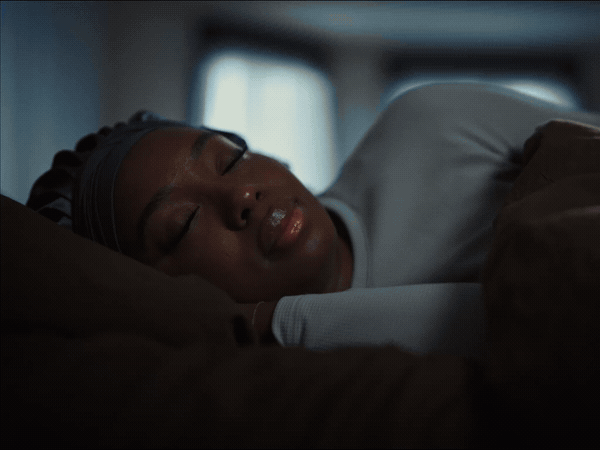 A woman sleeping peacefully in bed, wearing a sleep cap.