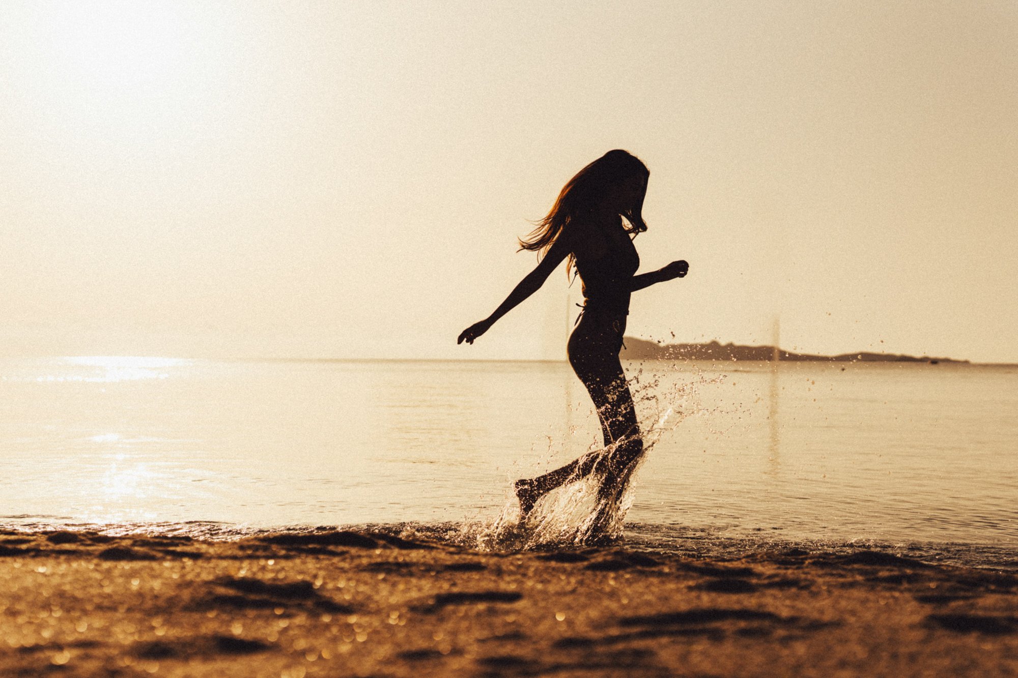 Donna che corre sulle onde a riva al tramonto.