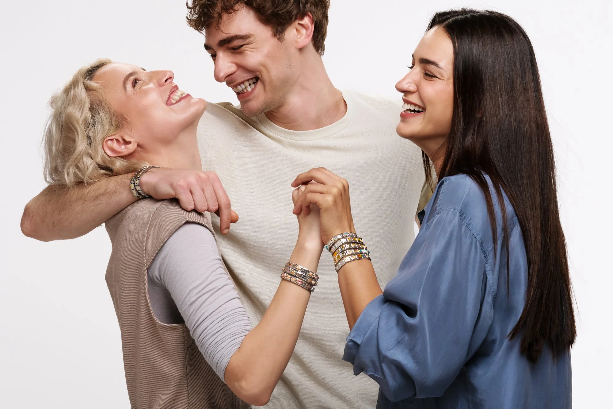 Tre persone sorridenti si abbracciano e si tengono per mano, mostrando affetto e gioia.