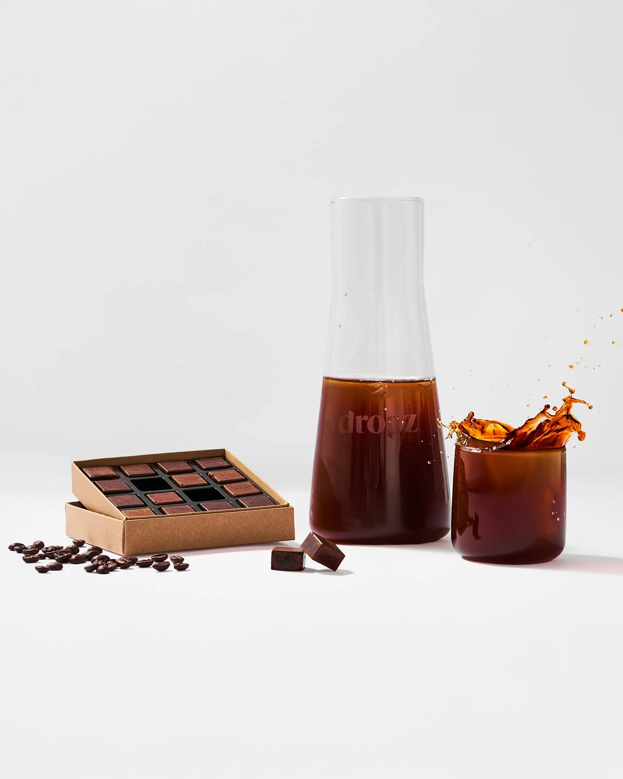 Tavolo con cioccolato, chicchi di caffè e una bottiglia e un bicchiere di caffè freddo
