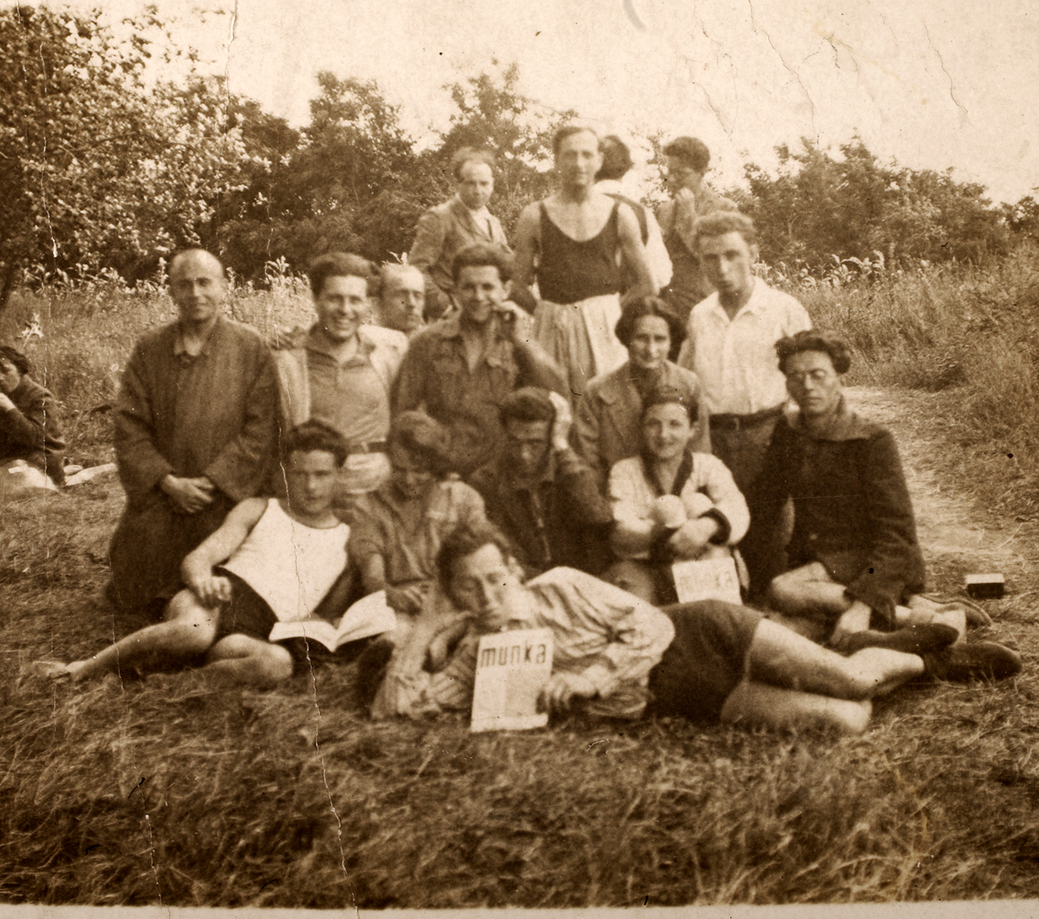 A group of hikers posing for a photograph outdoors, holding a journal.