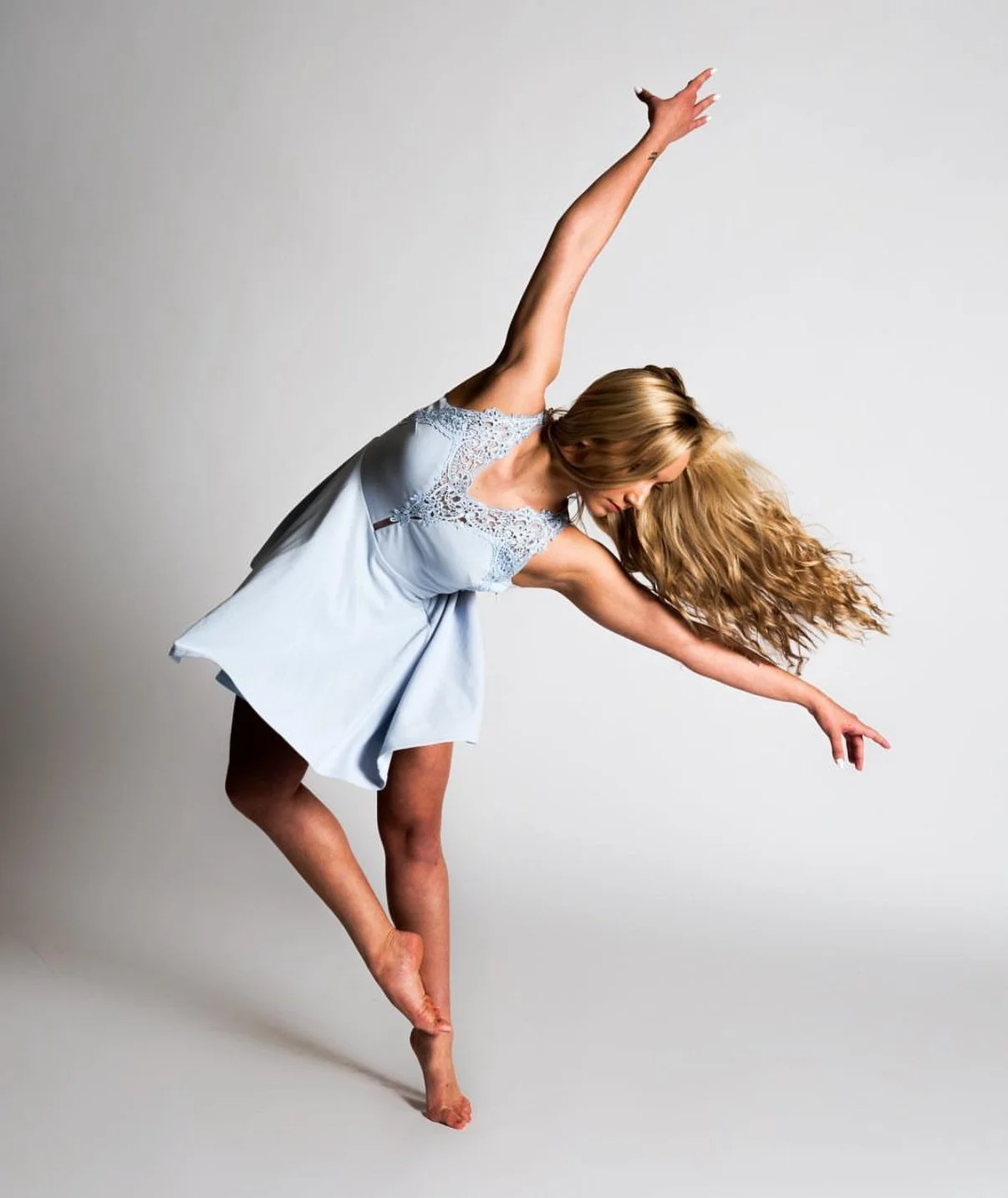 Two women dancing with graceful poses on a plain background.