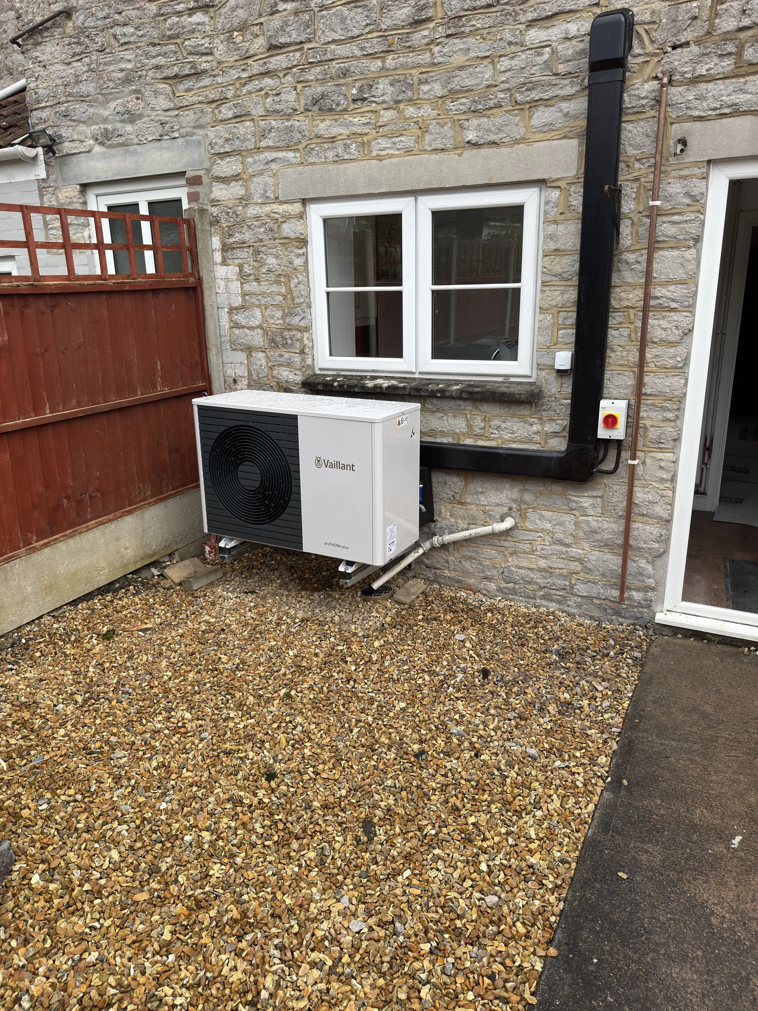 An Vaillant air source heat pump outside a house installed on a wall bracket