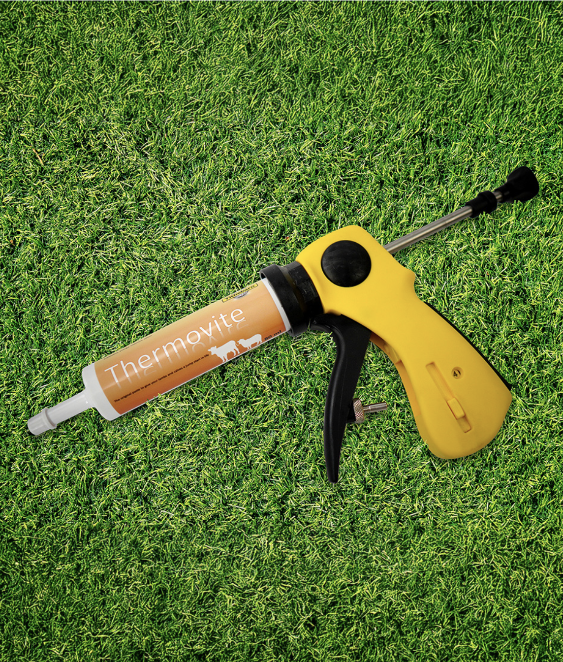 A caulking gun with a bottle labeled 'Thermovite' on a grassy surface.