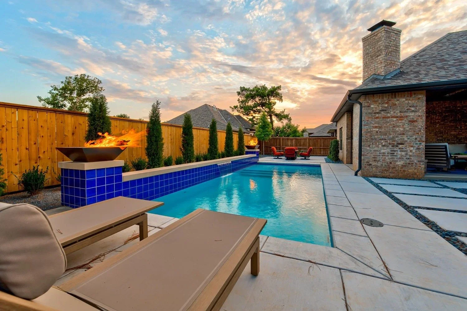 Backyard with swimming pool, fire feature, patio furniture, and sunset sky