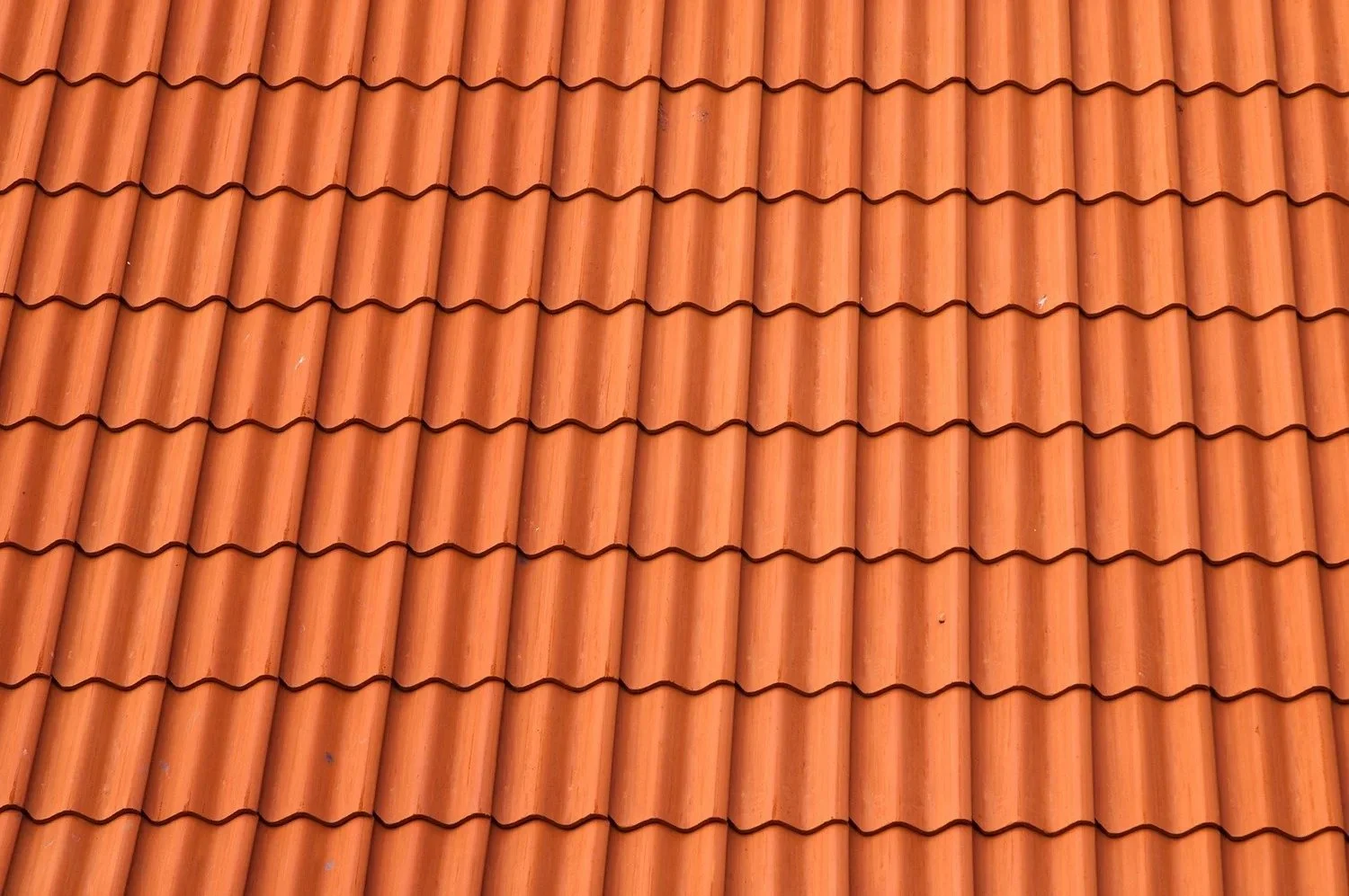 Close-up of a red clay tile roof with wavy, interlocking tiles.