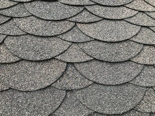 Close-up of asphalt roof shingles arranged in overlapping curved rows.