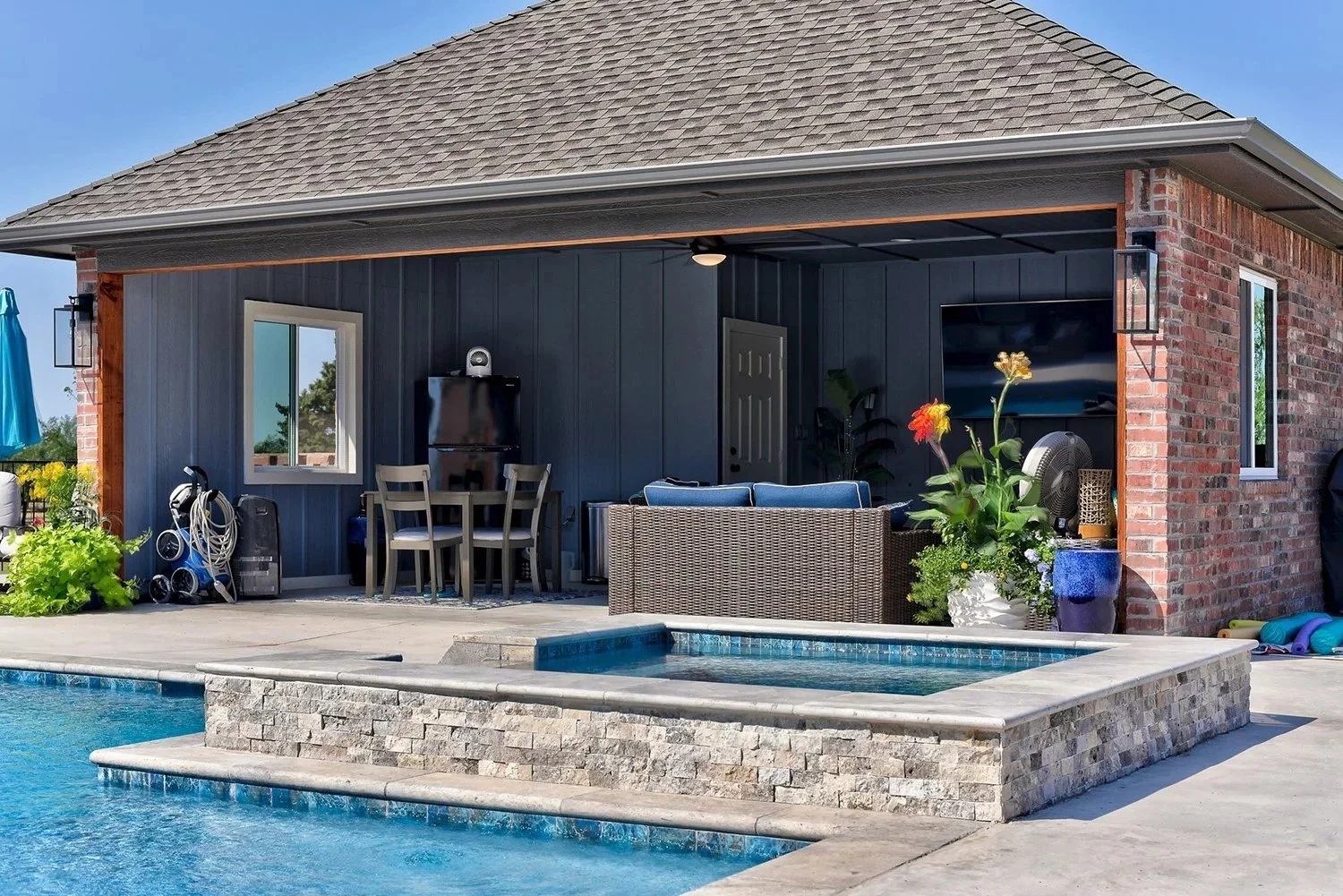 Backyard patio with a swimming pool, hot tub, outdoor furniture, plants, and a covered area with a dining table and chairs.