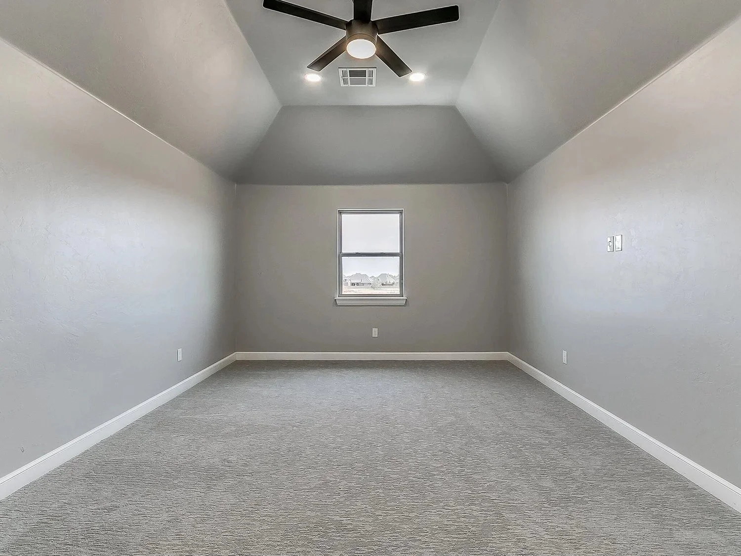 Empty room with gray walls, beige carpet, a small window, a ceiling fan with lights, and wall outlets.