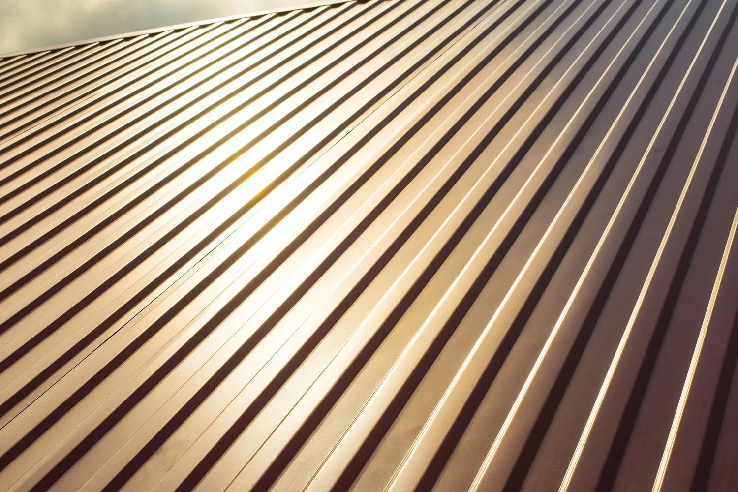 Close-up of parallel metal slats on a building's exterior, reflecting sunlight.