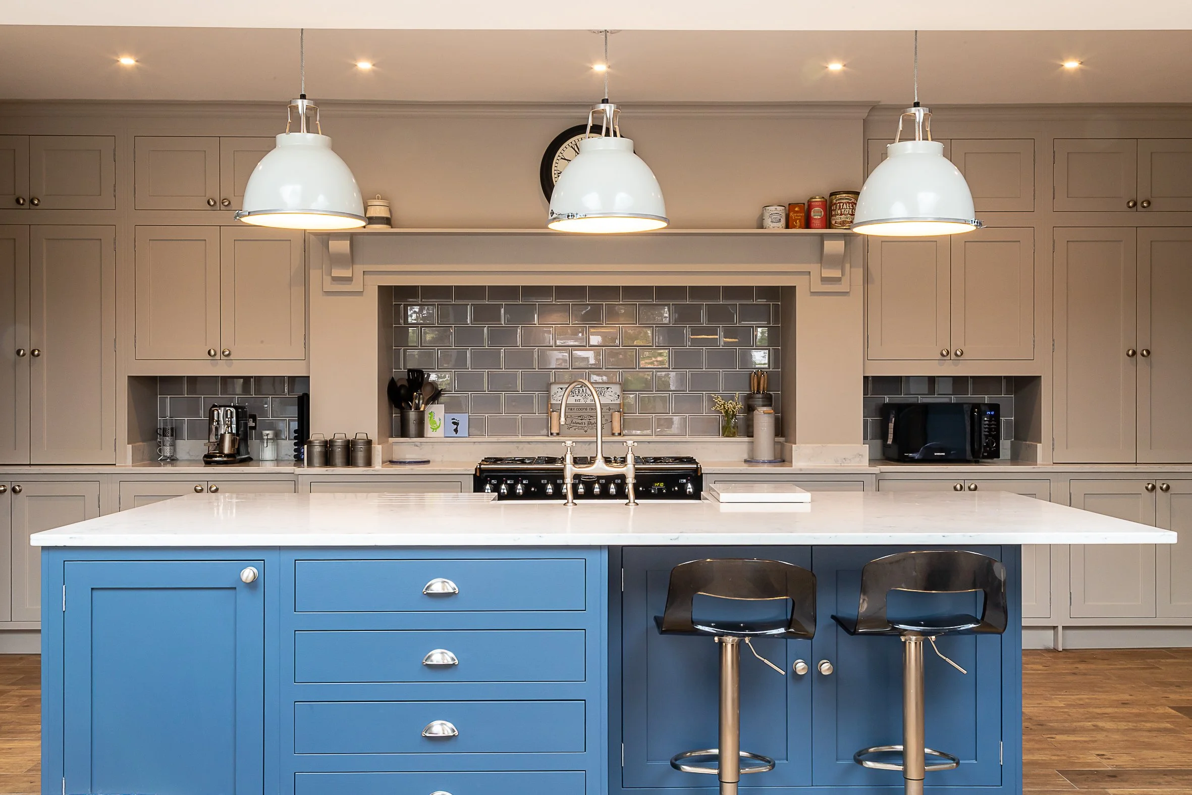 Modern kitchen with gray cabinetry, a blue kitchen island, gray subway tile backsplash, and pendant lighting.