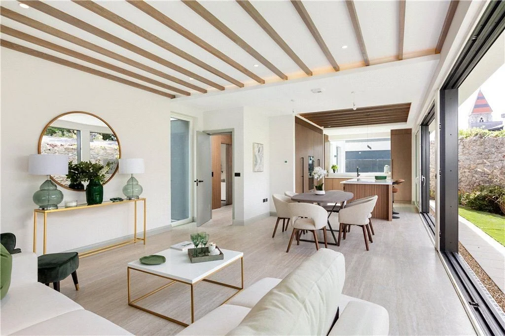 Open-concept living and dining area with modern decor, large sliding glass doors leading to a backyard, and a view of a neighboring house with a turret.