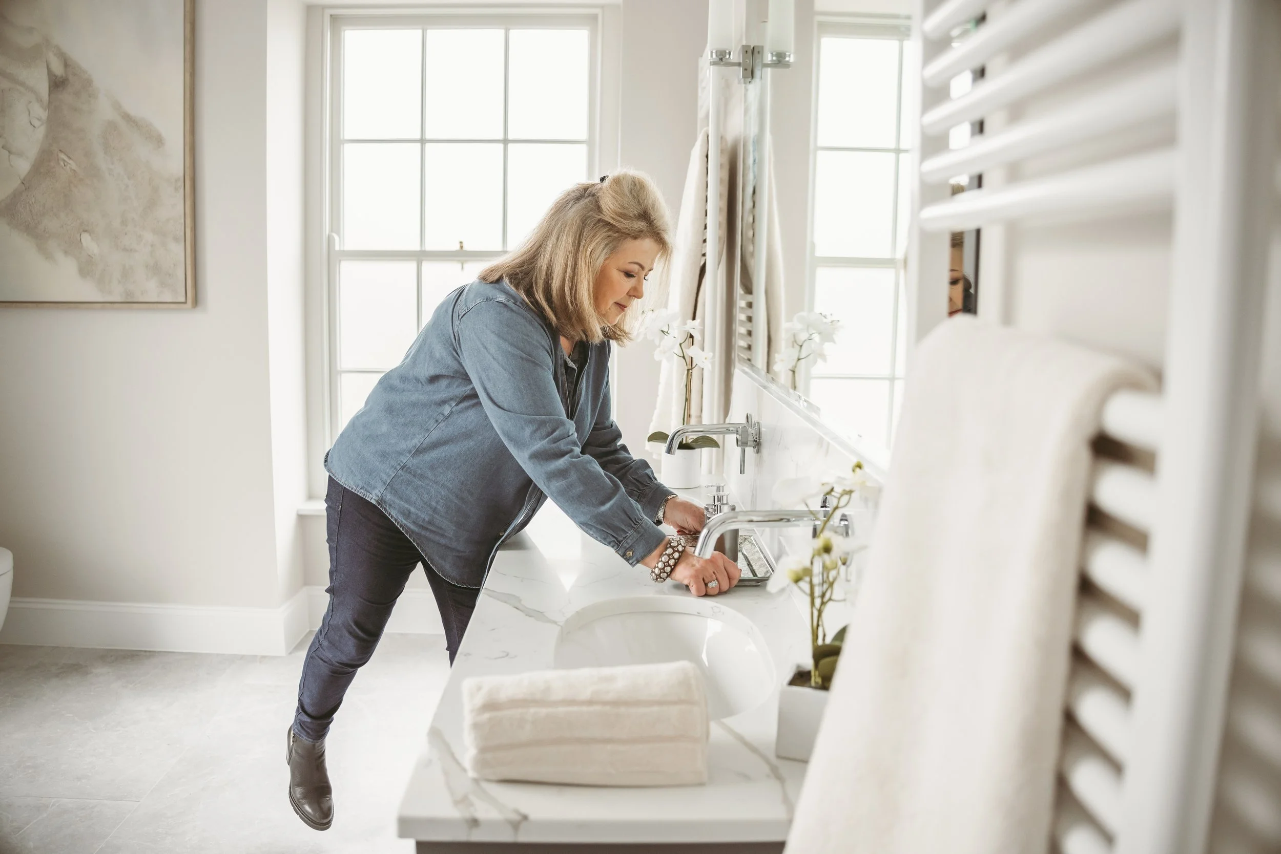 Woman washing dishes at a kitchen sink near window