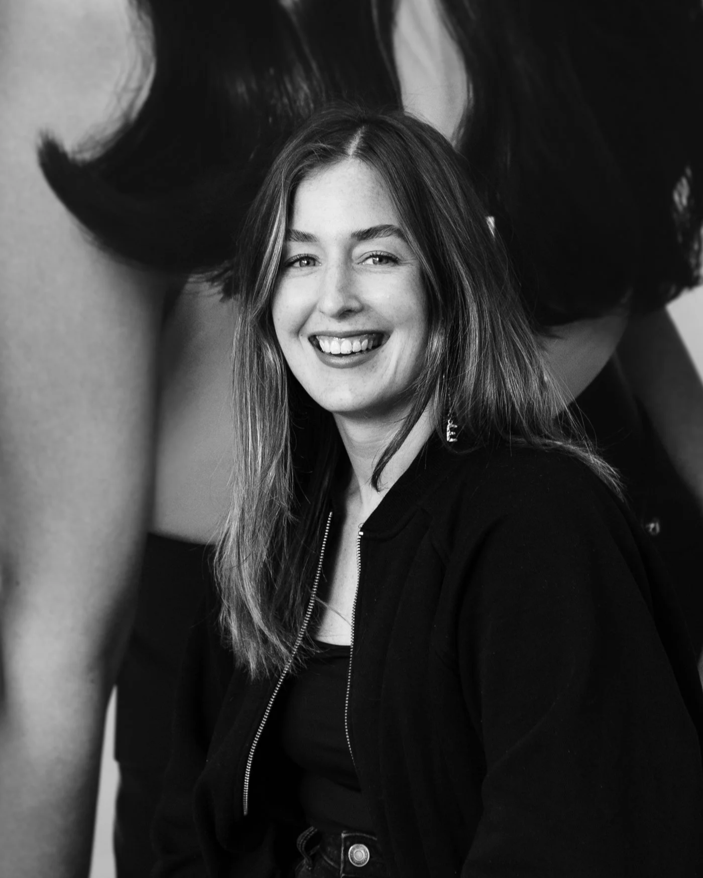 A woman with long hair smiling in a black and white photo.