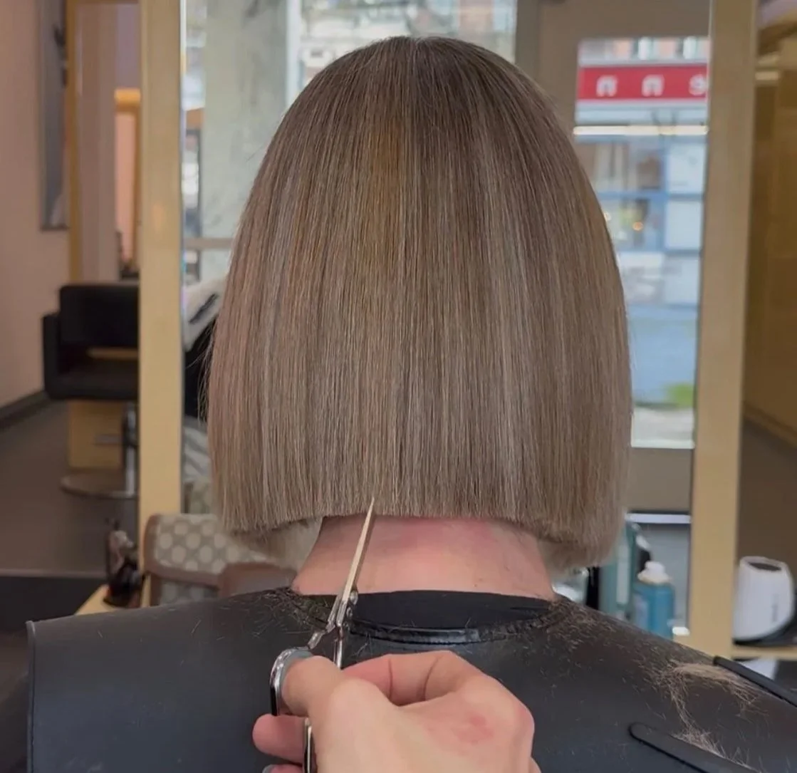 Person having a chin-length bob haircut cut and styled with scissors by a hairstylist in a salon.