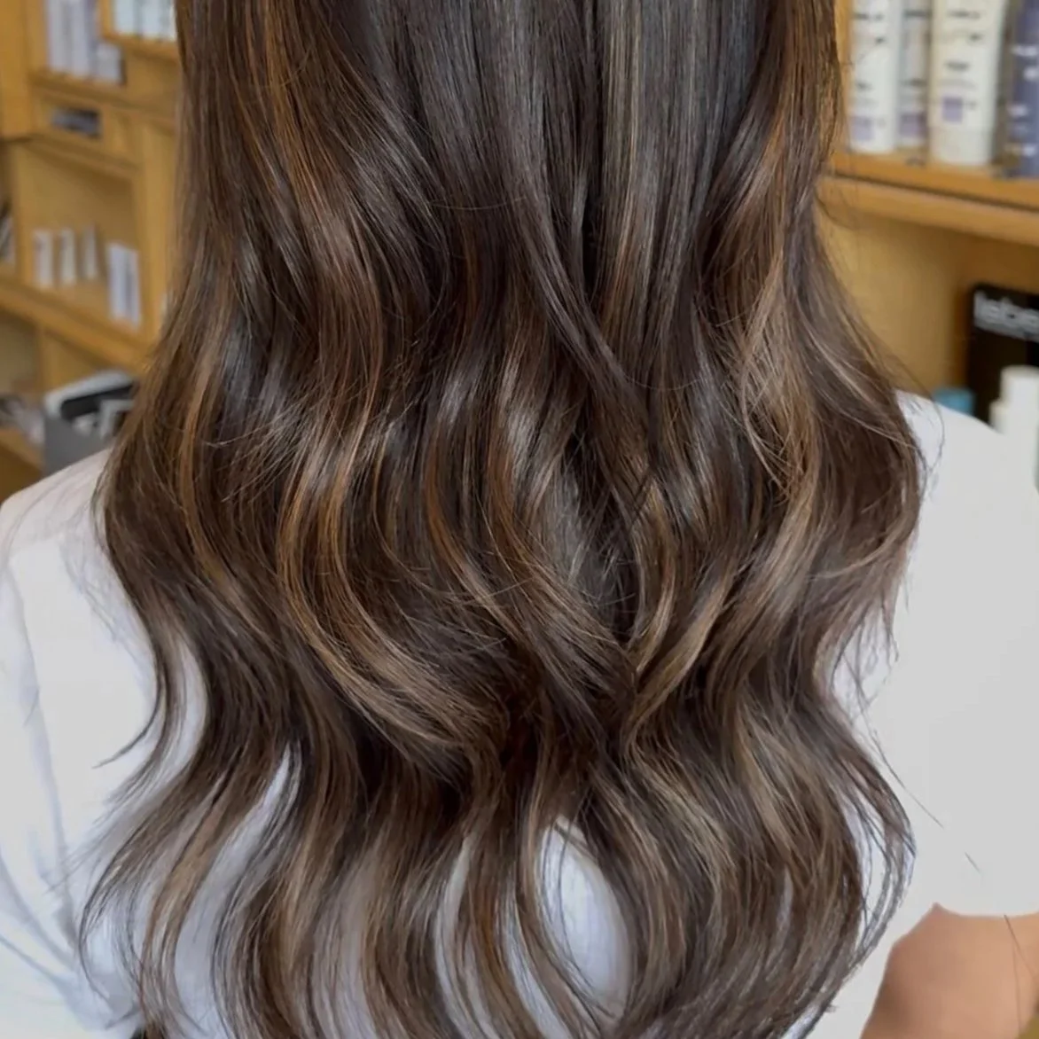Wavy medium-length brown hair with highlights, viewed from the back.