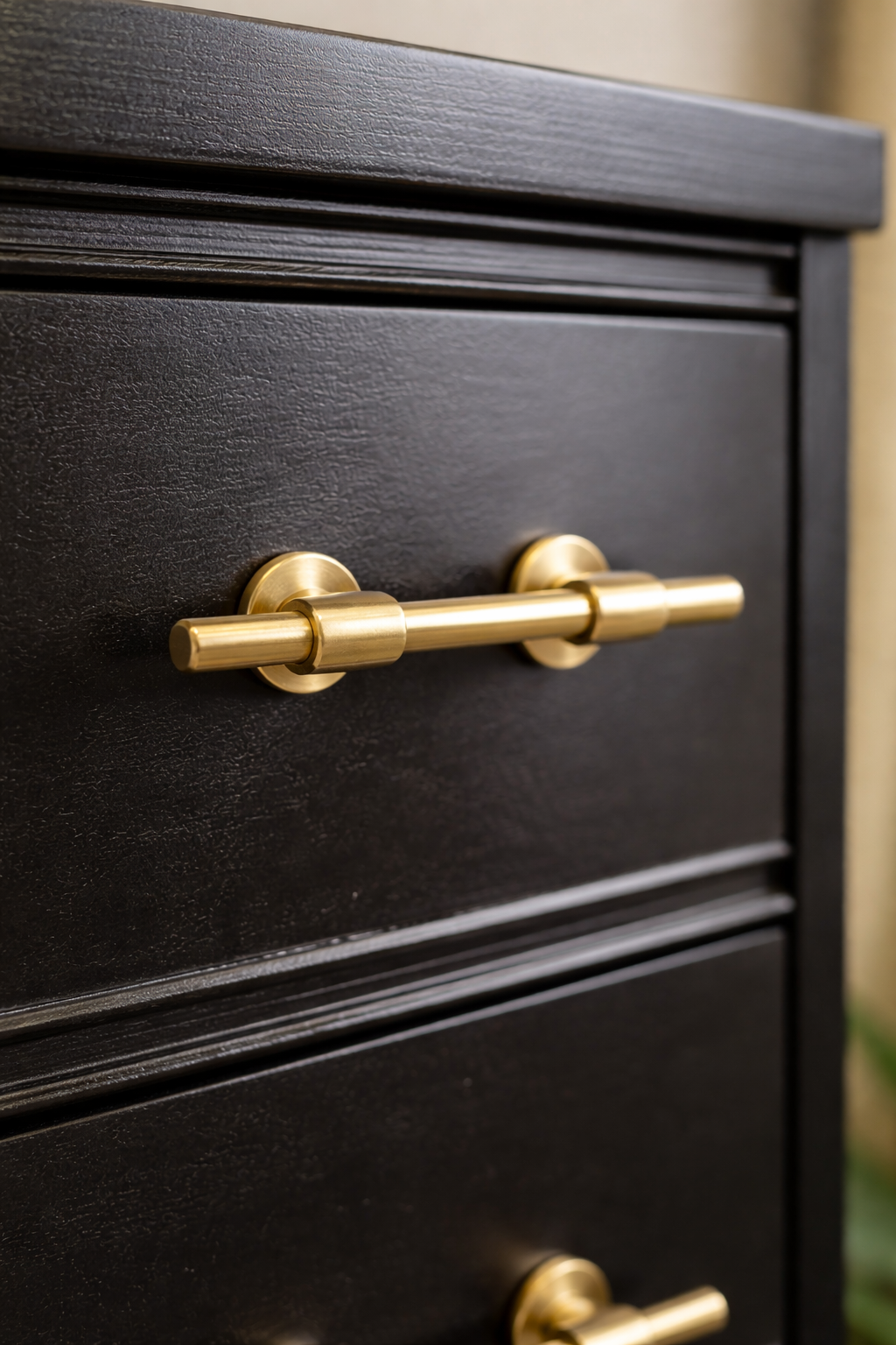 Close-up of a black wooden cabinet with horizontal grooves and a gold-colored handle.