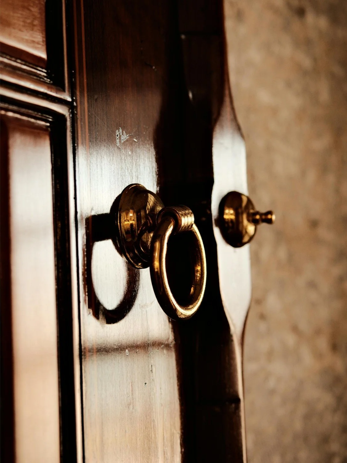 Close-up of a vintage brass drawer knob on a wooden furniture piece.