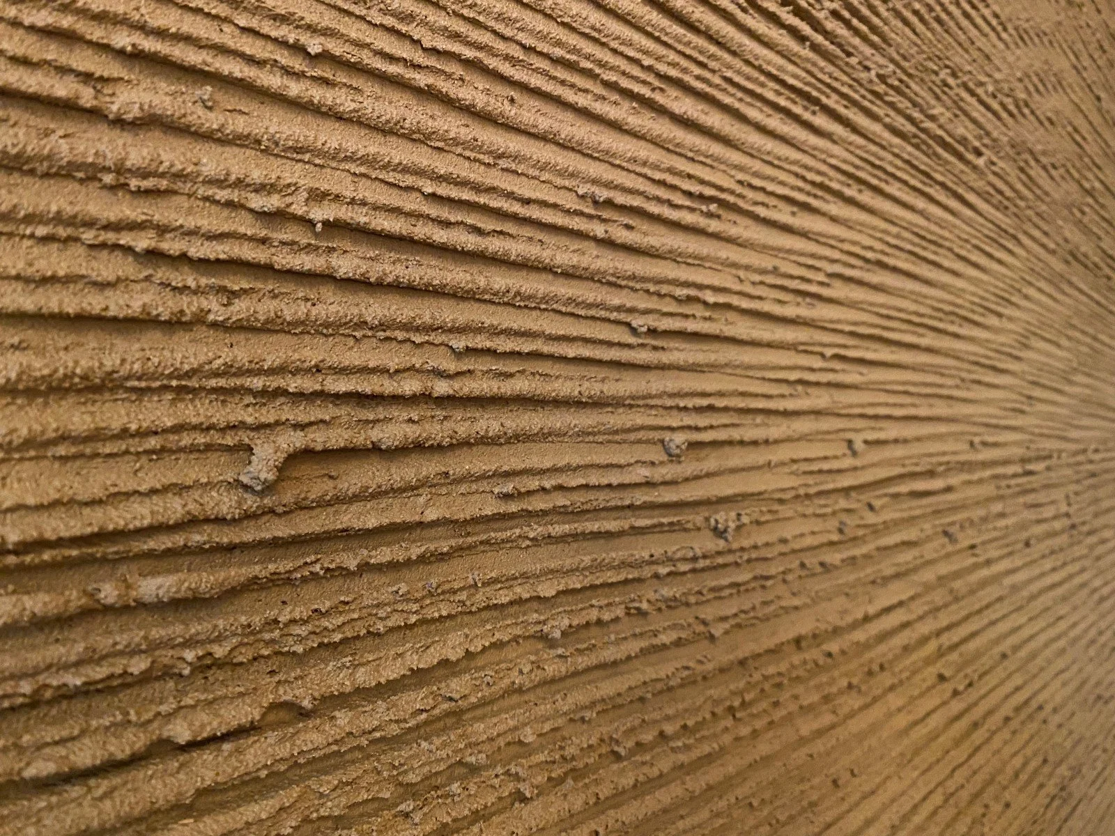 Detail van natuurlijke leemstuc met karakteristieke textuur en aardetinten