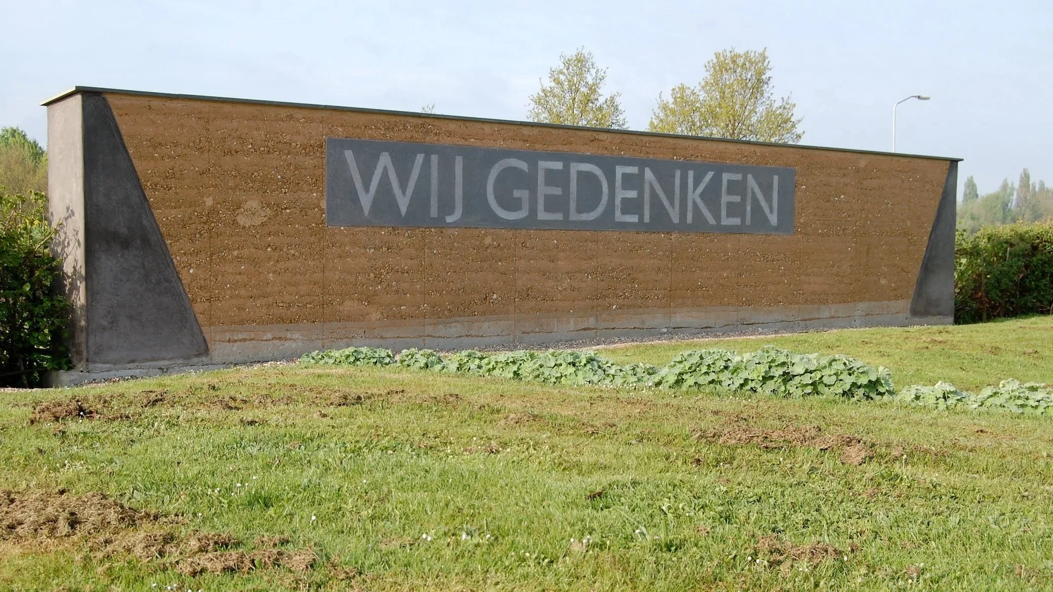 Stampleem gedenkmuur op gemeentelijke begraafplaats Spijk met natuurlijke aardlagen en warme uitstraling