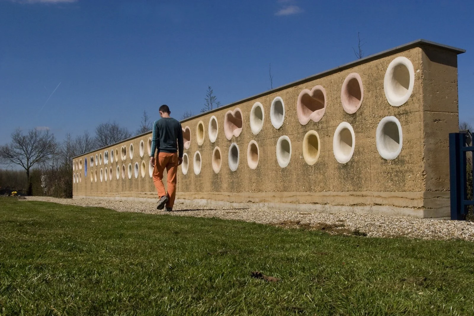 Urnenmuur van gestampte aarde met zichtbare aardlagen en karaktervolle stampleem textuur