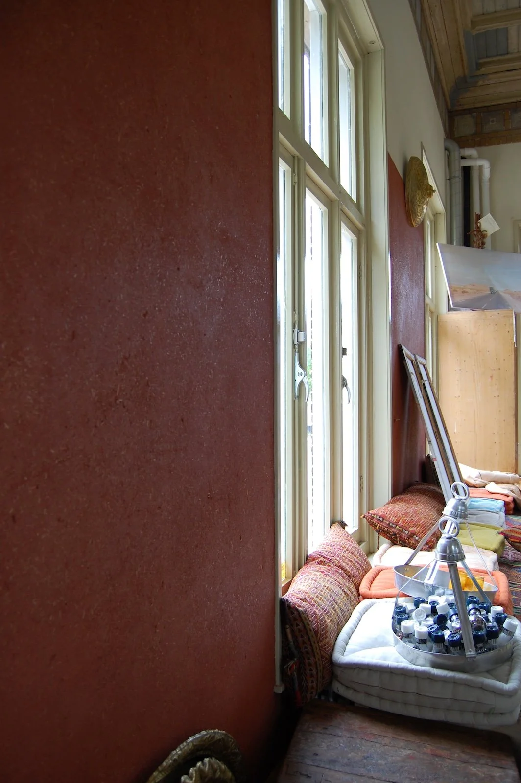 Detail van leemstuc wand met organische textuur, rode pigmenten en zichtbare strovezels