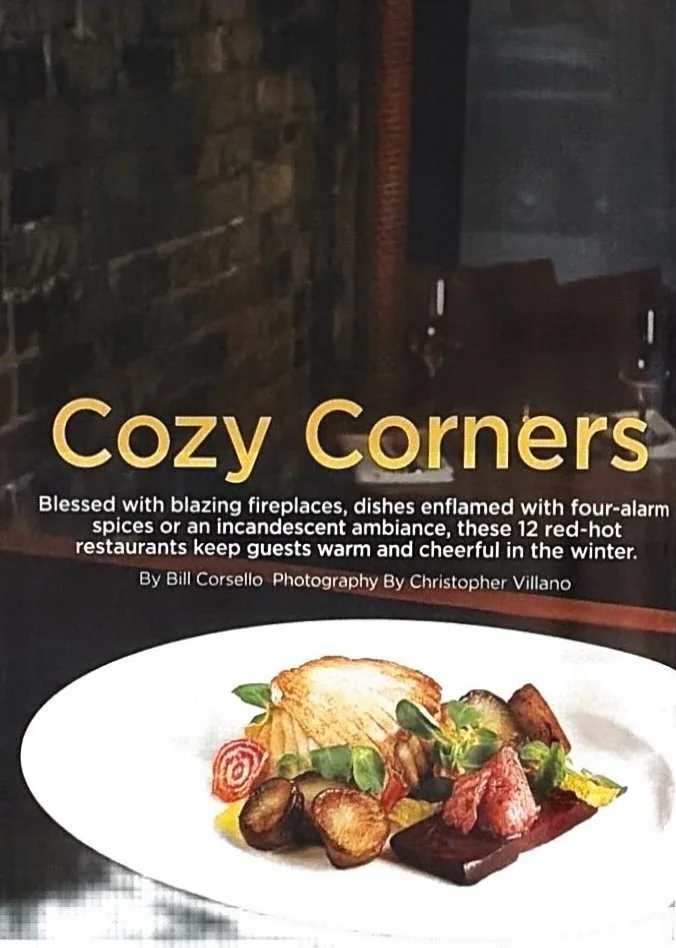 A restaurant menu cover titled "Cozy Corners" with a description about fireplaces and hot foods for winter, and an image of a plated dish with roasted vegetables, bread, and garnishes.