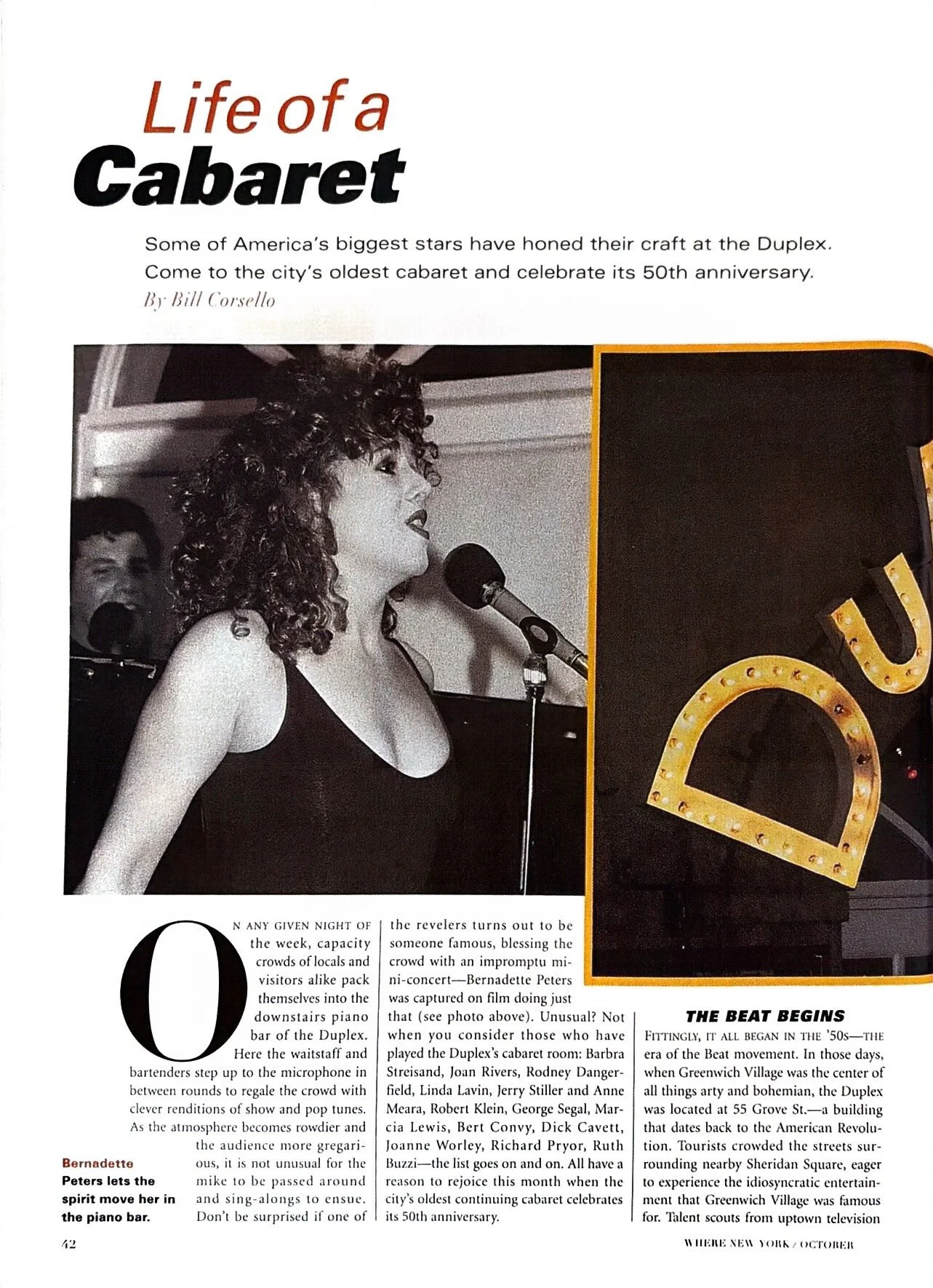 Black and white photo of a woman singing into a microphone at a cabaret, with a pianist visible in the background, and a large illuminated 'DUX' sign on the right.
